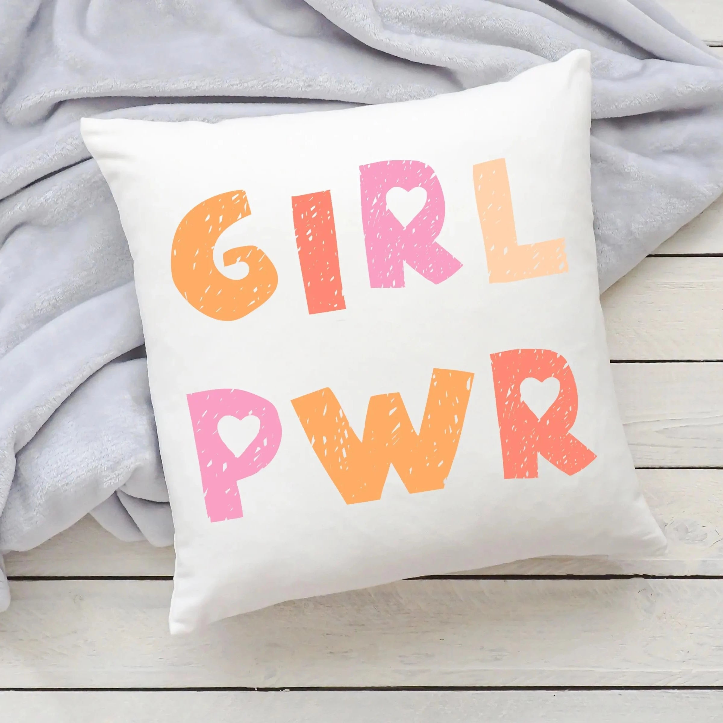 White throw pillow with girl pwr printed in colorful textured orange and pink letters with heart shapes inside the rs