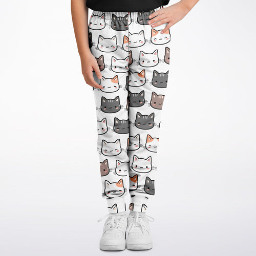 Girls cat jogger pants in white featuring a playful pattern of gray white and orange cartoon cat faces