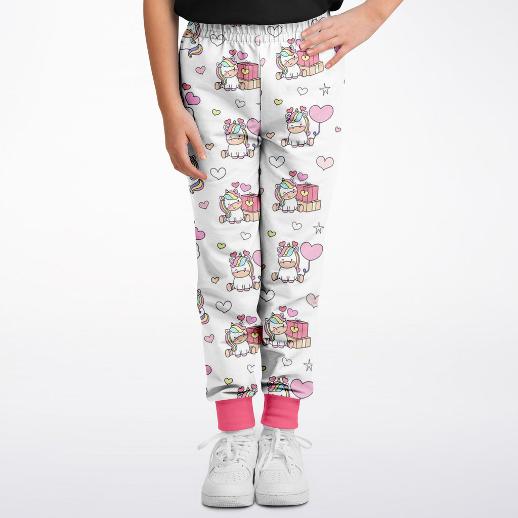 Girls unicorn birthday jogger pants in white with playful cartoon unicorn and heart pattern and pink cuffs