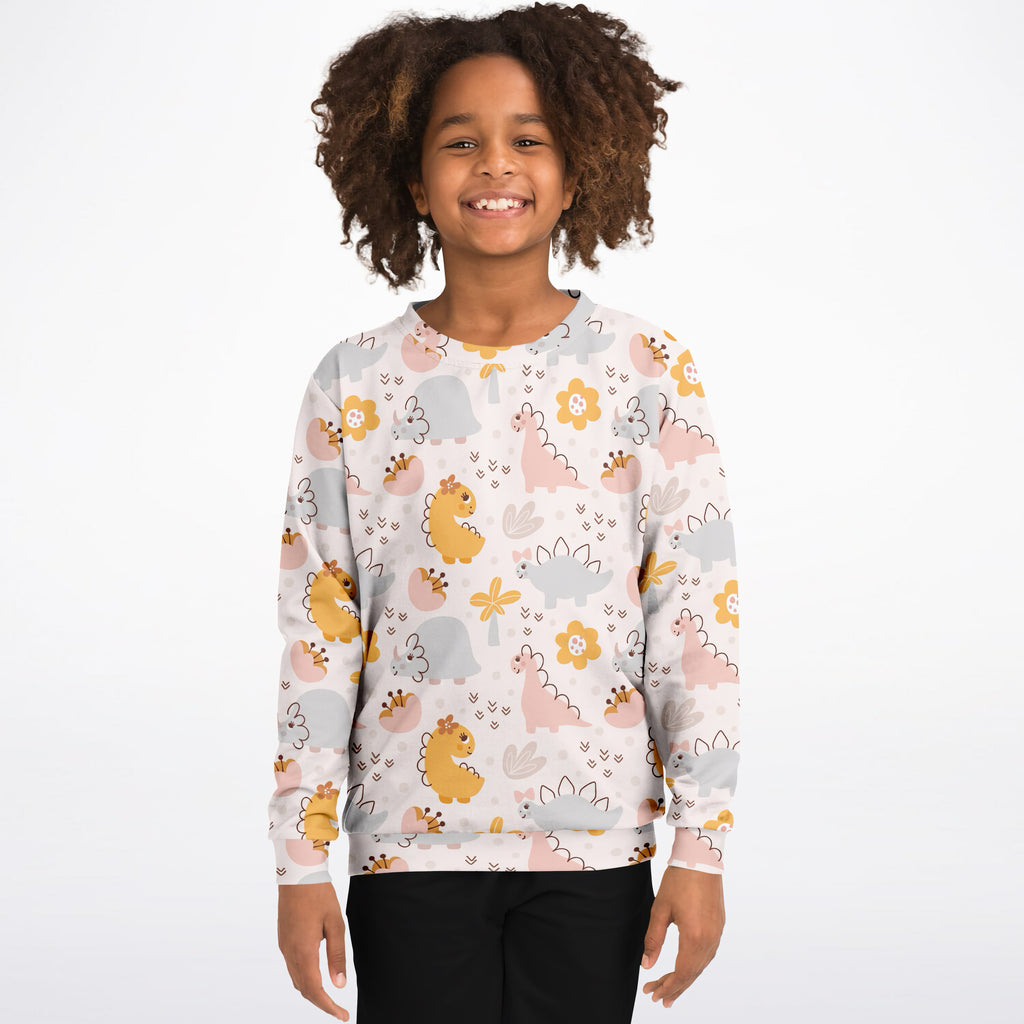 A child wearing a girls floral dinosaur sweatshirt in white cotton fleece with pastel dinosaur and flower patterns