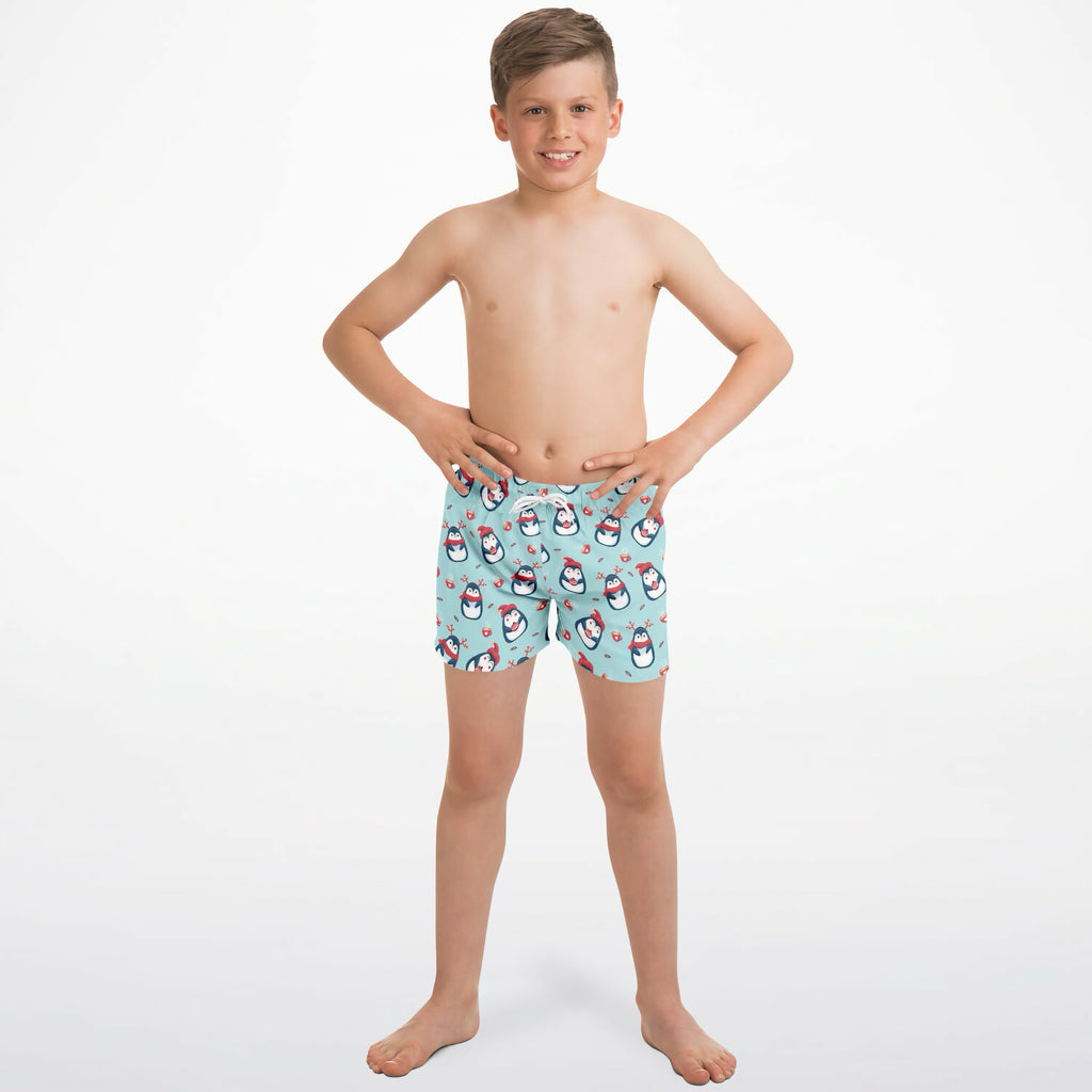 Light blue boys quick drying swim trunks with playful cartoon penguins wearing red hats holding hearts pattern