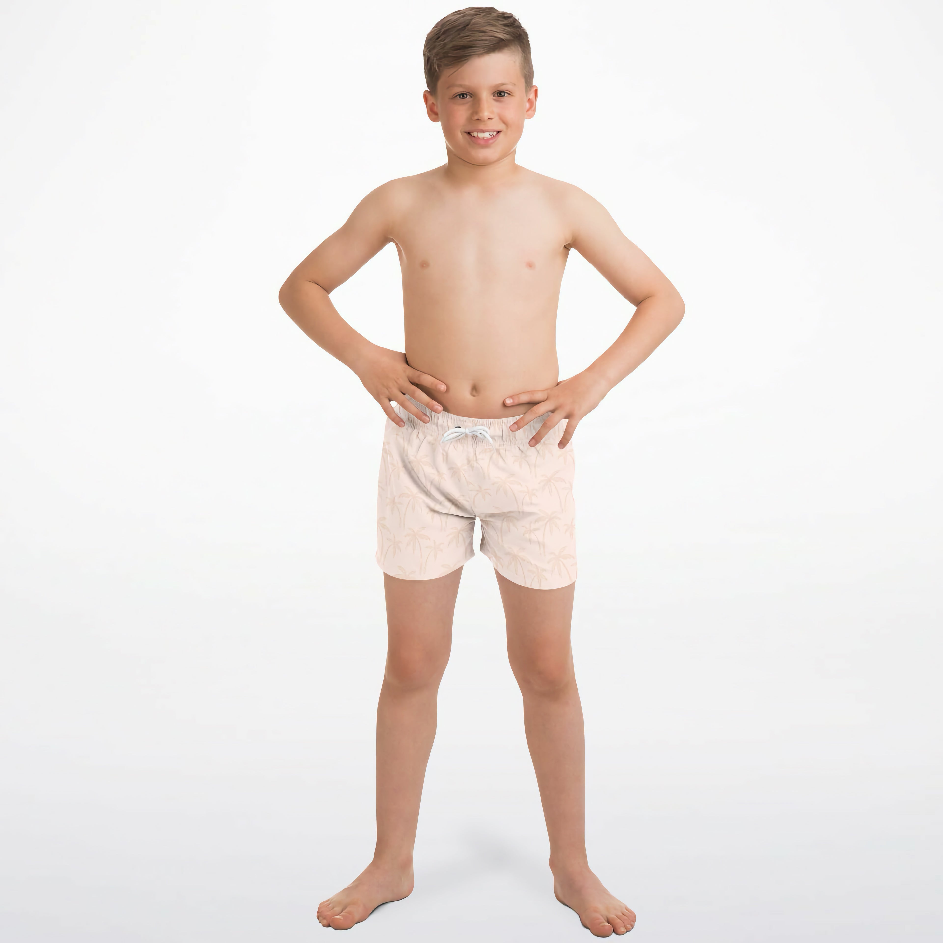 A boy wearing boys light peach palm tree quick drying swim trunks in light pink with white drawstring and subtle pattern