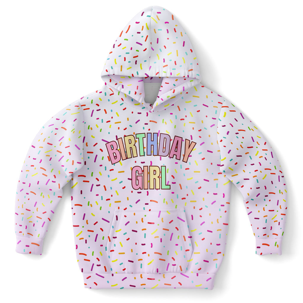 A white children’s hoodie with colorful sprinkles and rainbow birthday girl lettering in cozy cotton fleece fabric