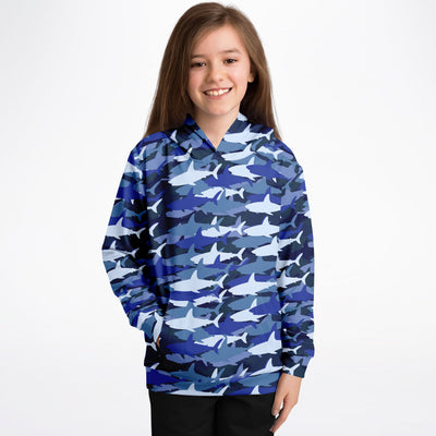 A young girl wearing a kids blue shark hoodie in cozy cotton fleece with blue and white camouflage design