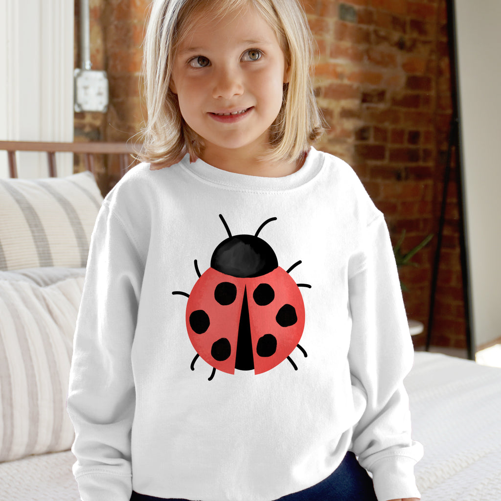 White kids long-sleeved sweatshirt with a red ladybug print featuring black spots and antennae on the front