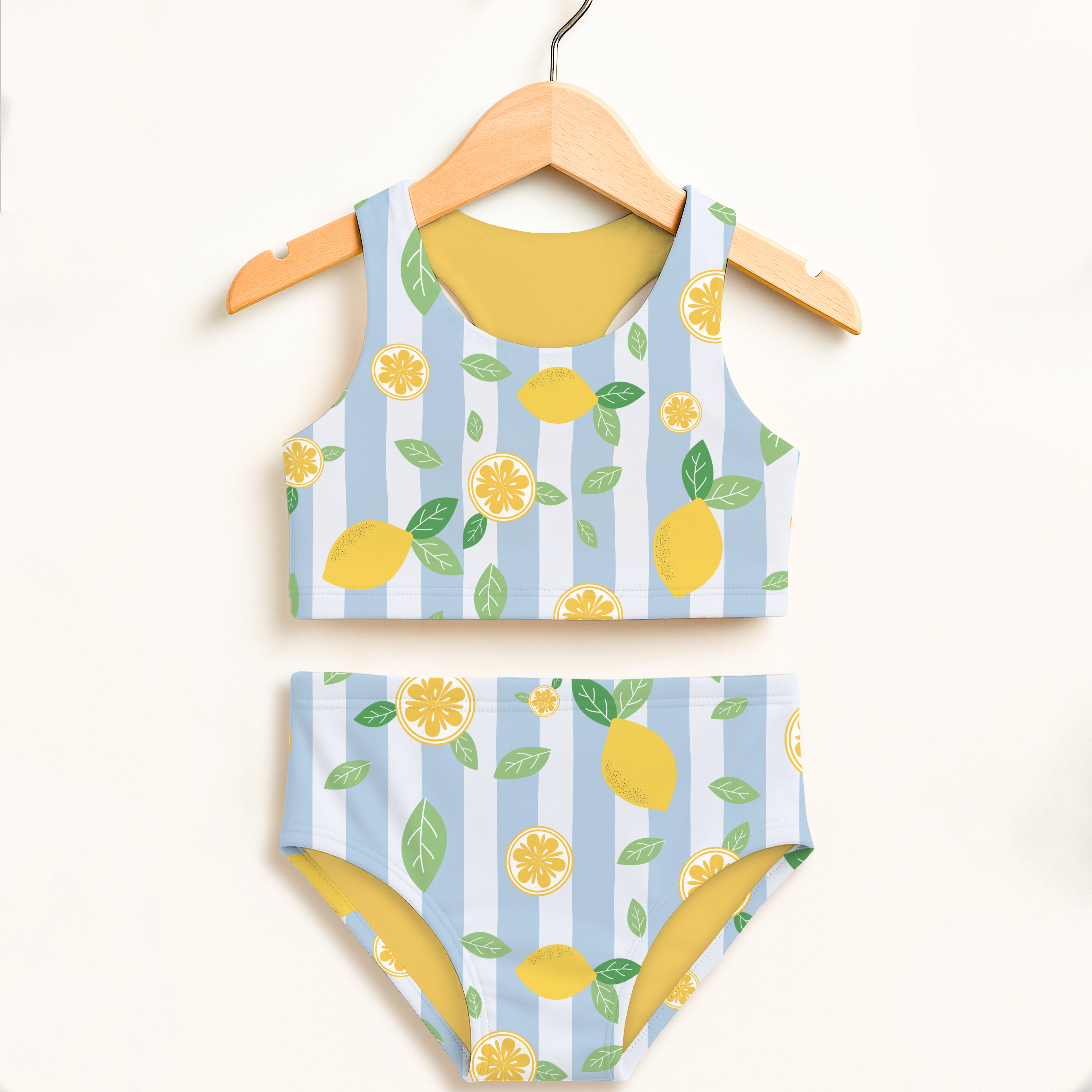 Children's swimsuit set with lemon pattern on a hanger against a white background