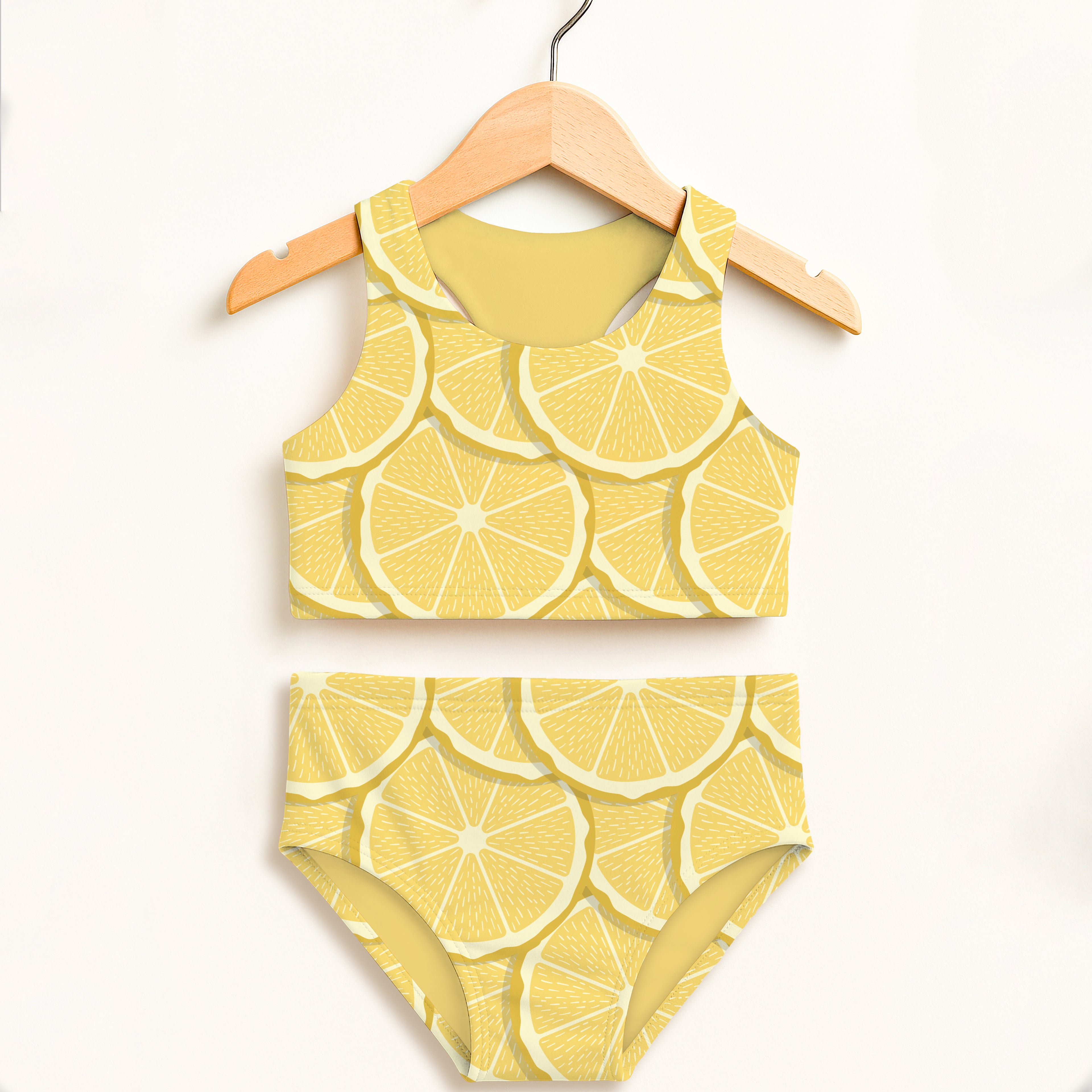 Yellow lemon slice patterned girls two piece swimsuit hanging on wooden hanger with upf 50 plus high waisted comfort