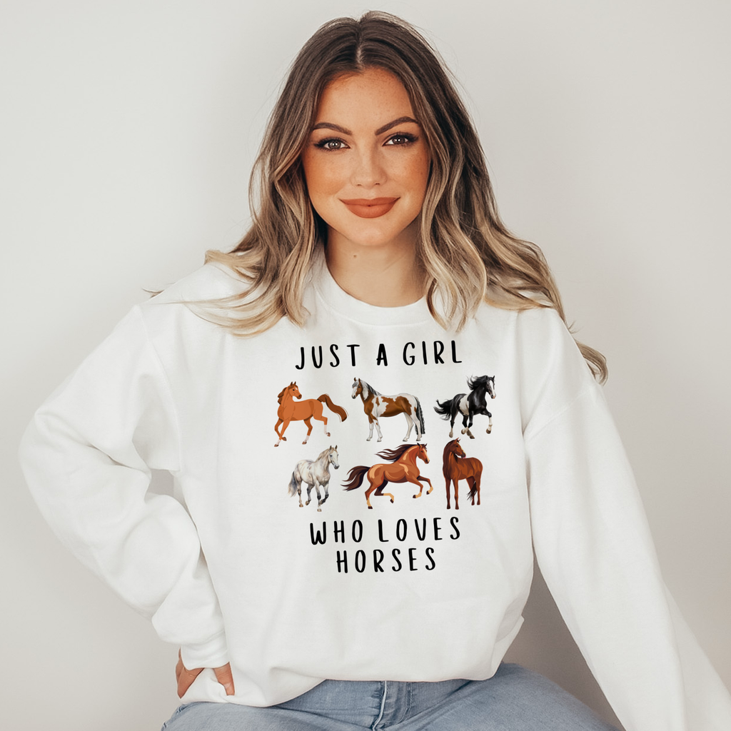 Woman wearing a white sweatshirt with horse illustrations and text on a plain background