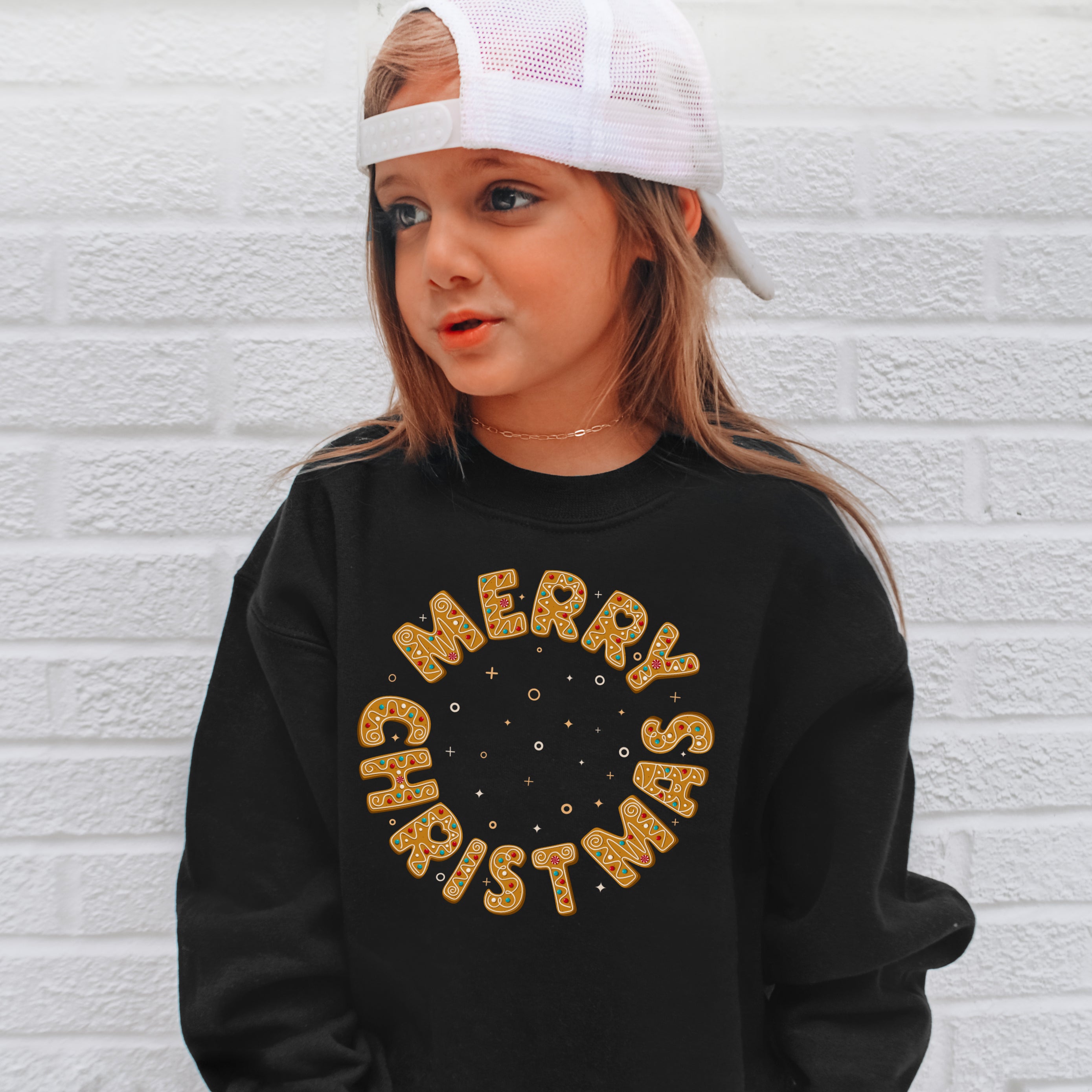 Black long-sleeved kids sweatshirt with merry christmas cookie dough style text and stars for festive holidays