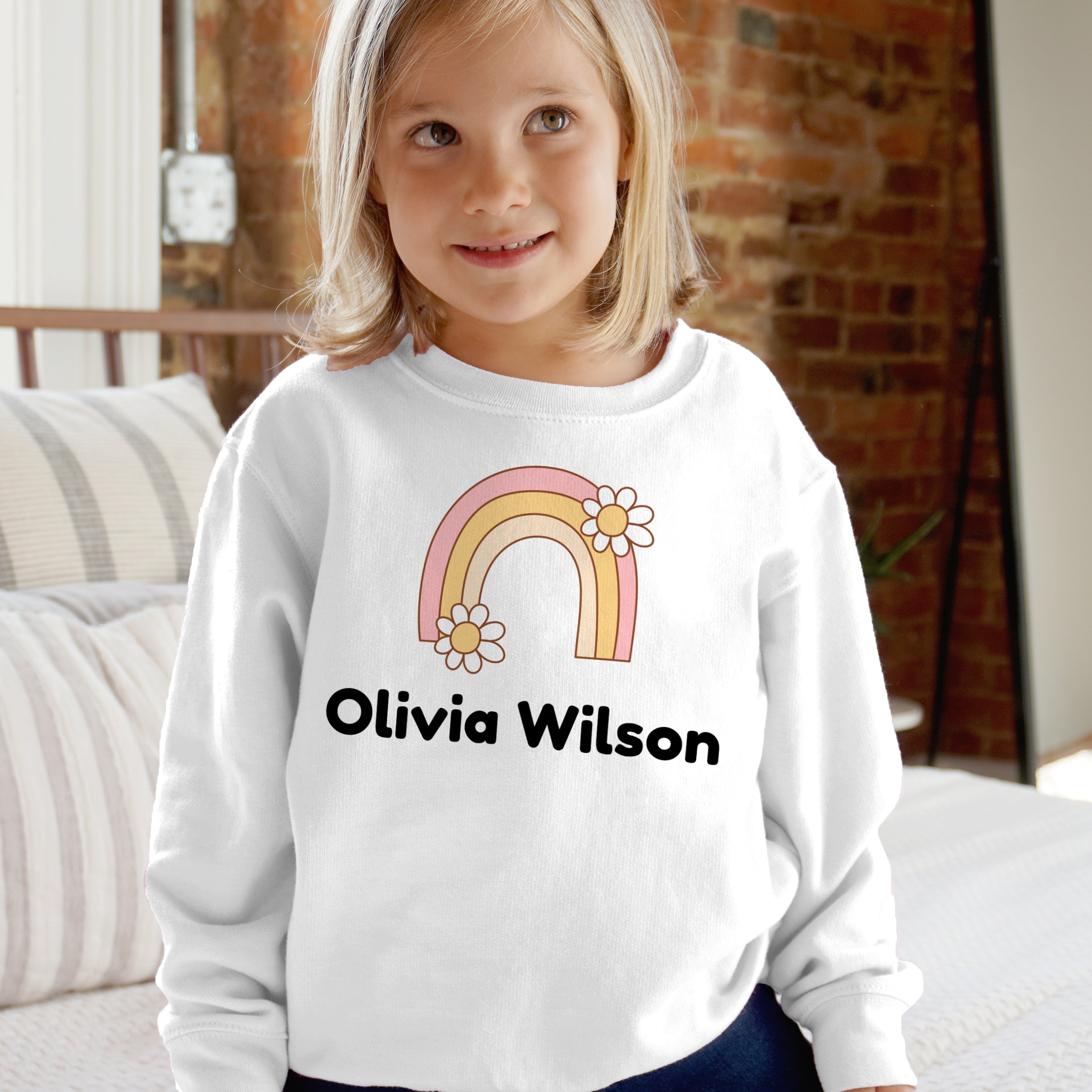 White long-sleeved sweatshirt with pastel rainbow and white daisies personalized with name olivia wilson