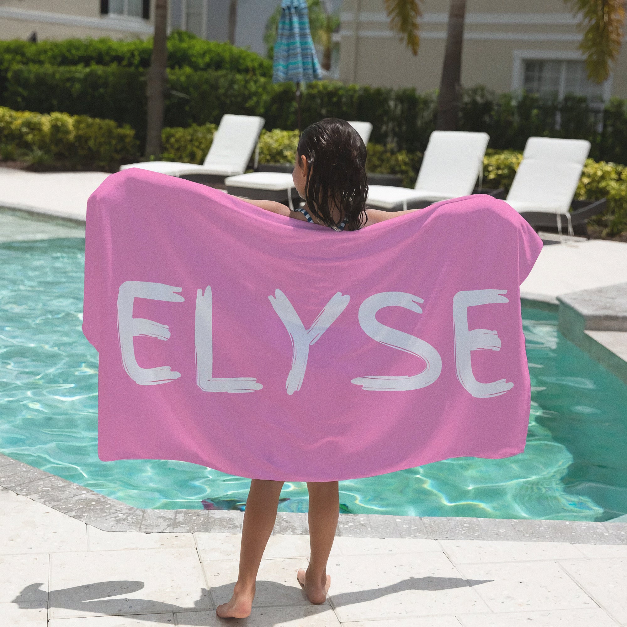 Pink kids custom name towel featuring white brushstroke style elyse lettering on a soft beach towel