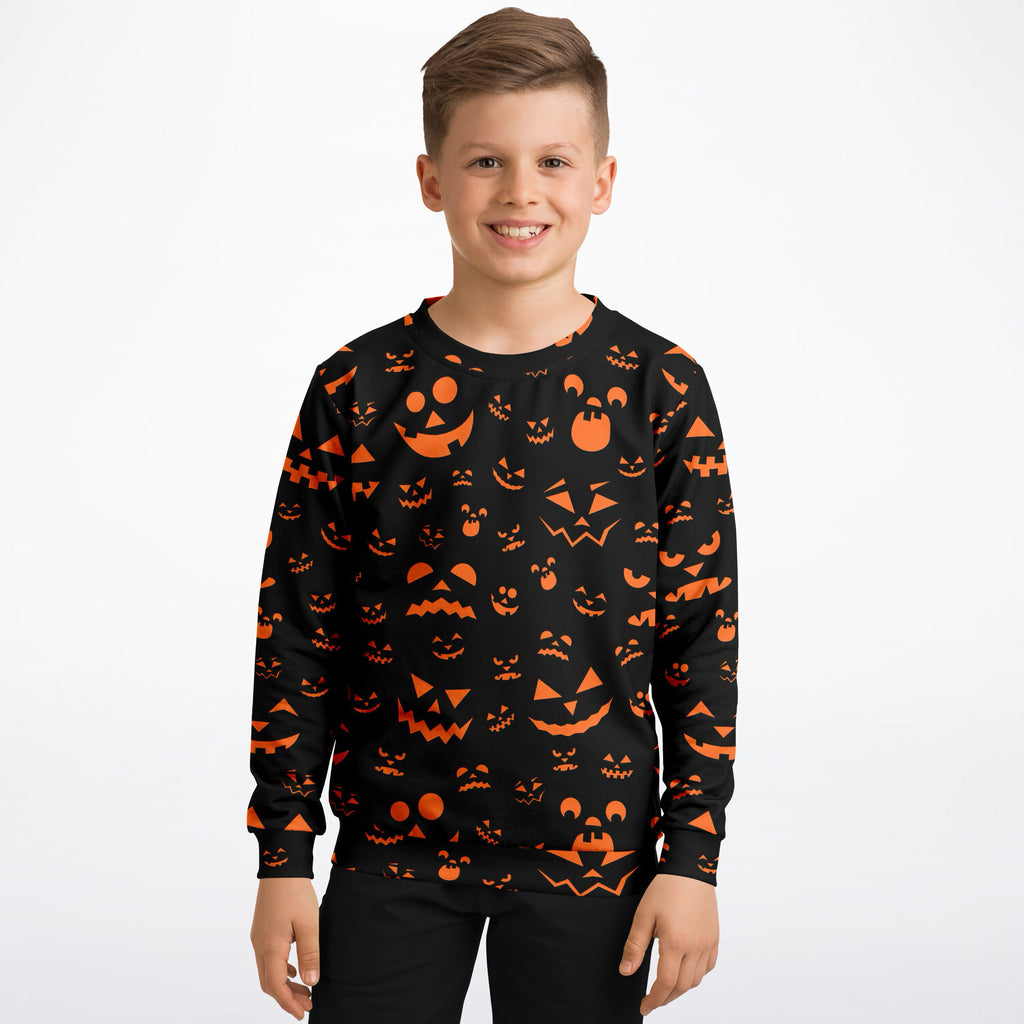 Black long-sleeved kids sweatshirt with vibrant orange halloween jack-o-lantern face made of cozy cotton fleece