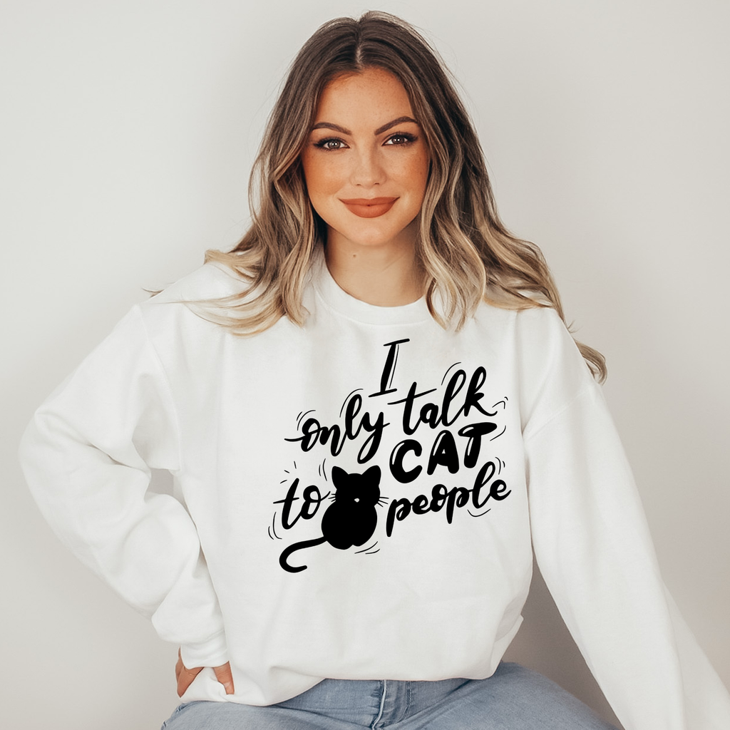 Woman wearing a white sweatshirt with black text and a cat graphic on a plain background