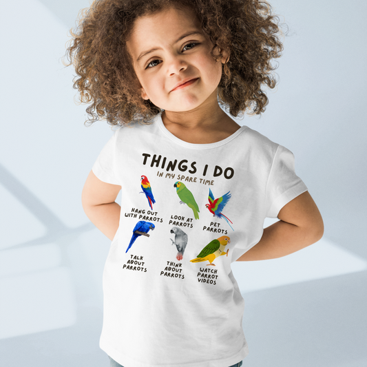 Child wearing a white t-shirt with colorful parrot illustrations and text.