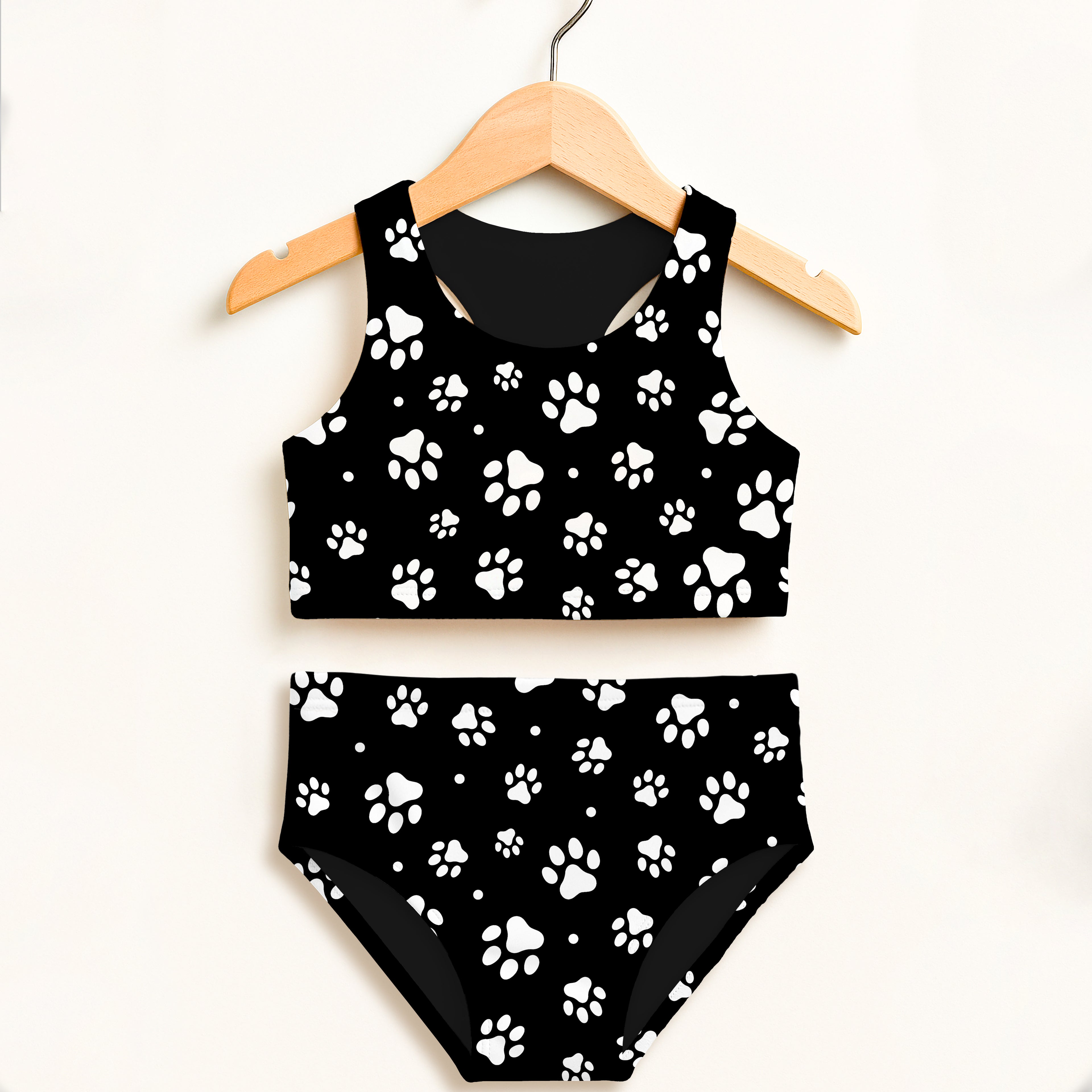 Girls black and white paw print two-piece swimsuit hanging on wooden hanger with double layered upf 50+ high waisted design