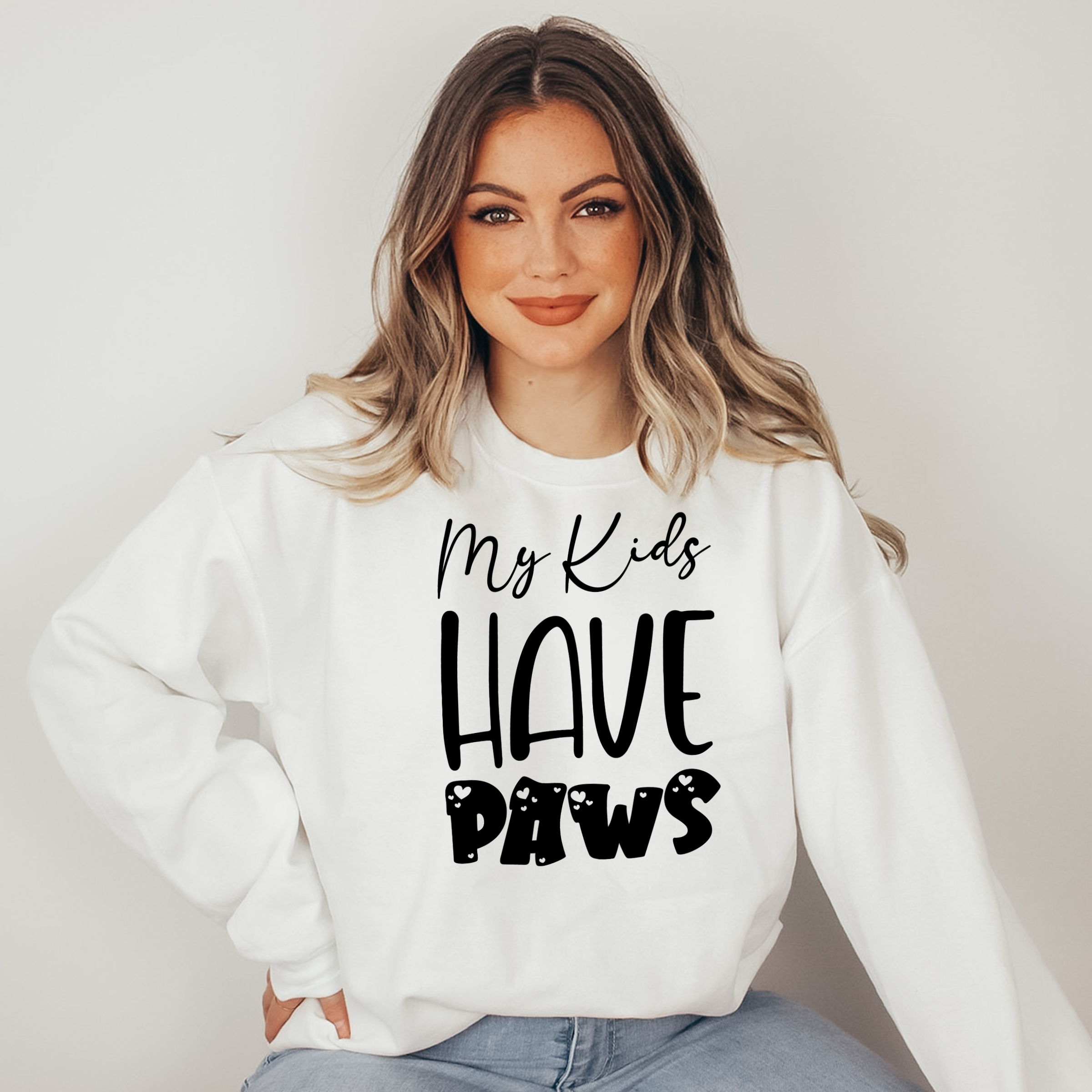 Woman wearing a white sweatshirt with 'My Kids Have Paws' text on a plain background