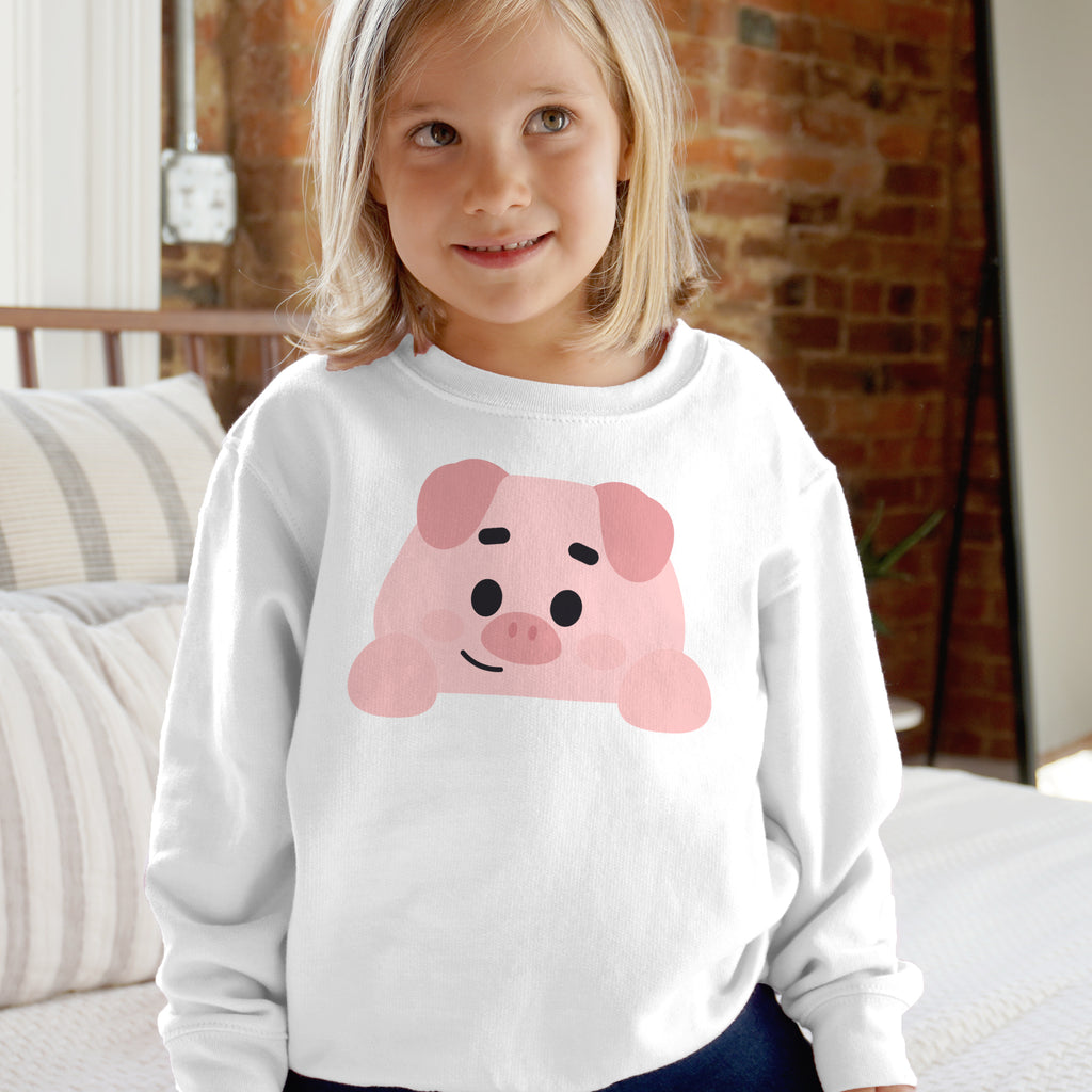 Child wearing a white sweatshirt with a pink pig design in a casual indoor setting.