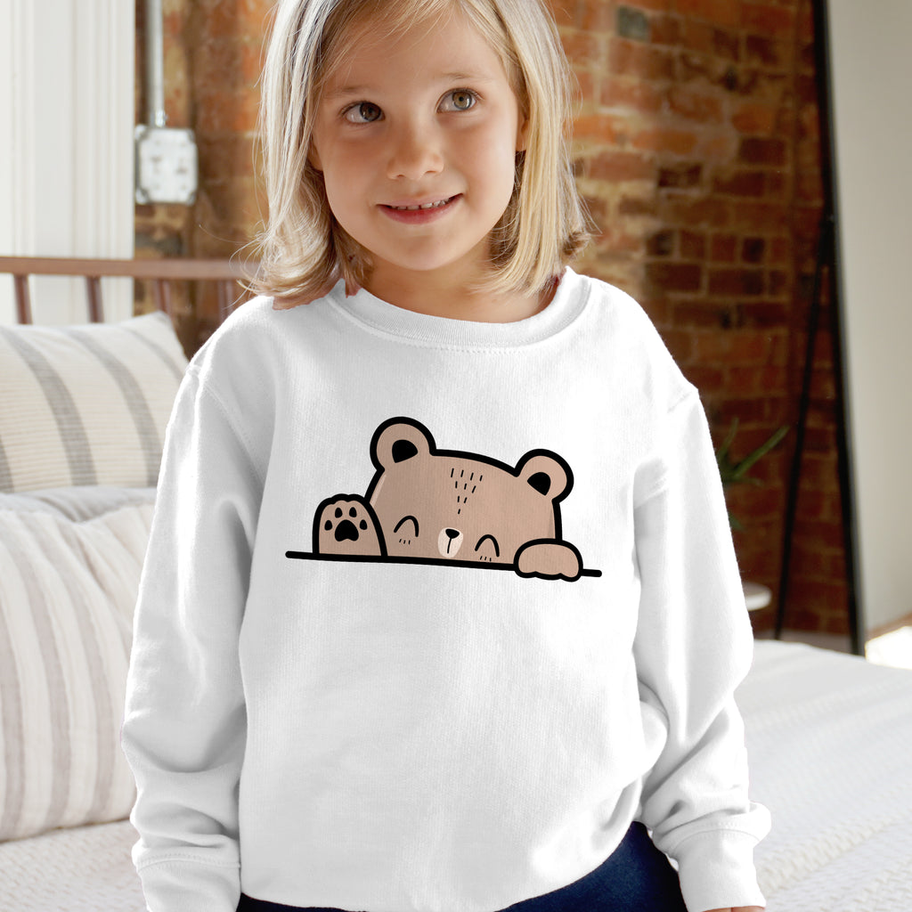 White long-sleeved kids sweatshirt with a cute beige bear peeking over the hem in cartoon style with black outlines