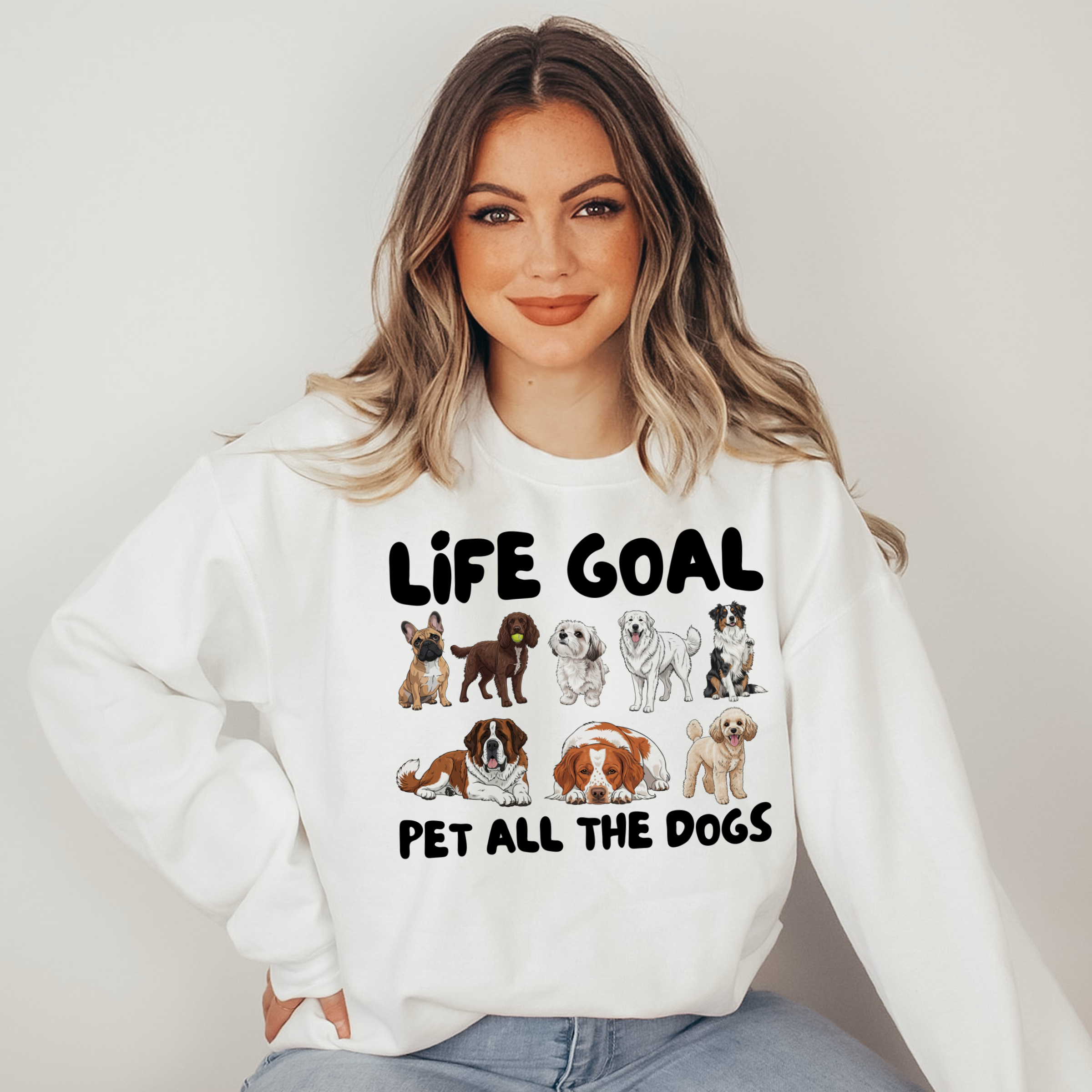 Woman wearing a white sweatshirt with dog illustrations and text on a plain background