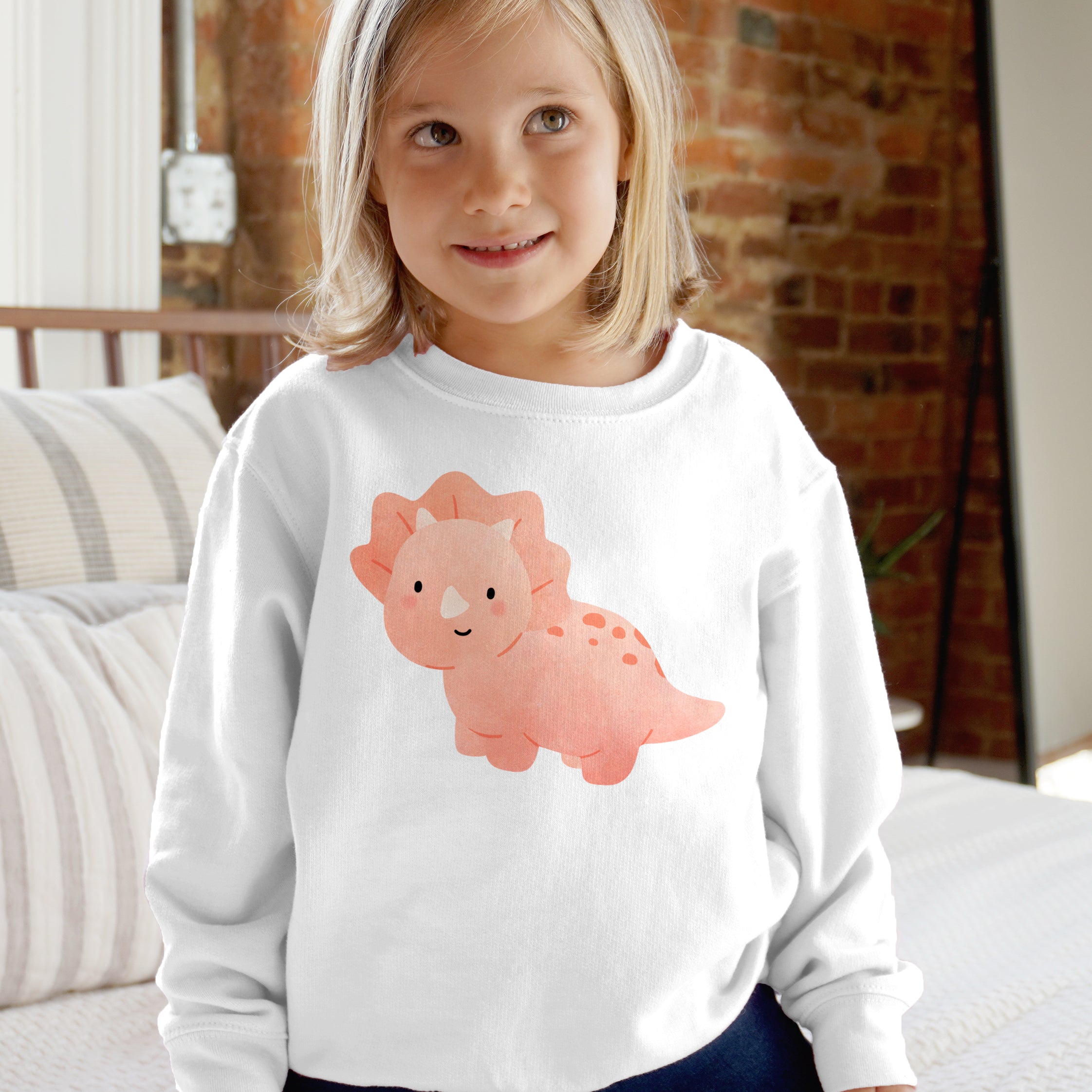 White long-sleeved girls sweatshirt with a pink cartoon triceratops graphic for toddlers and kids pullover