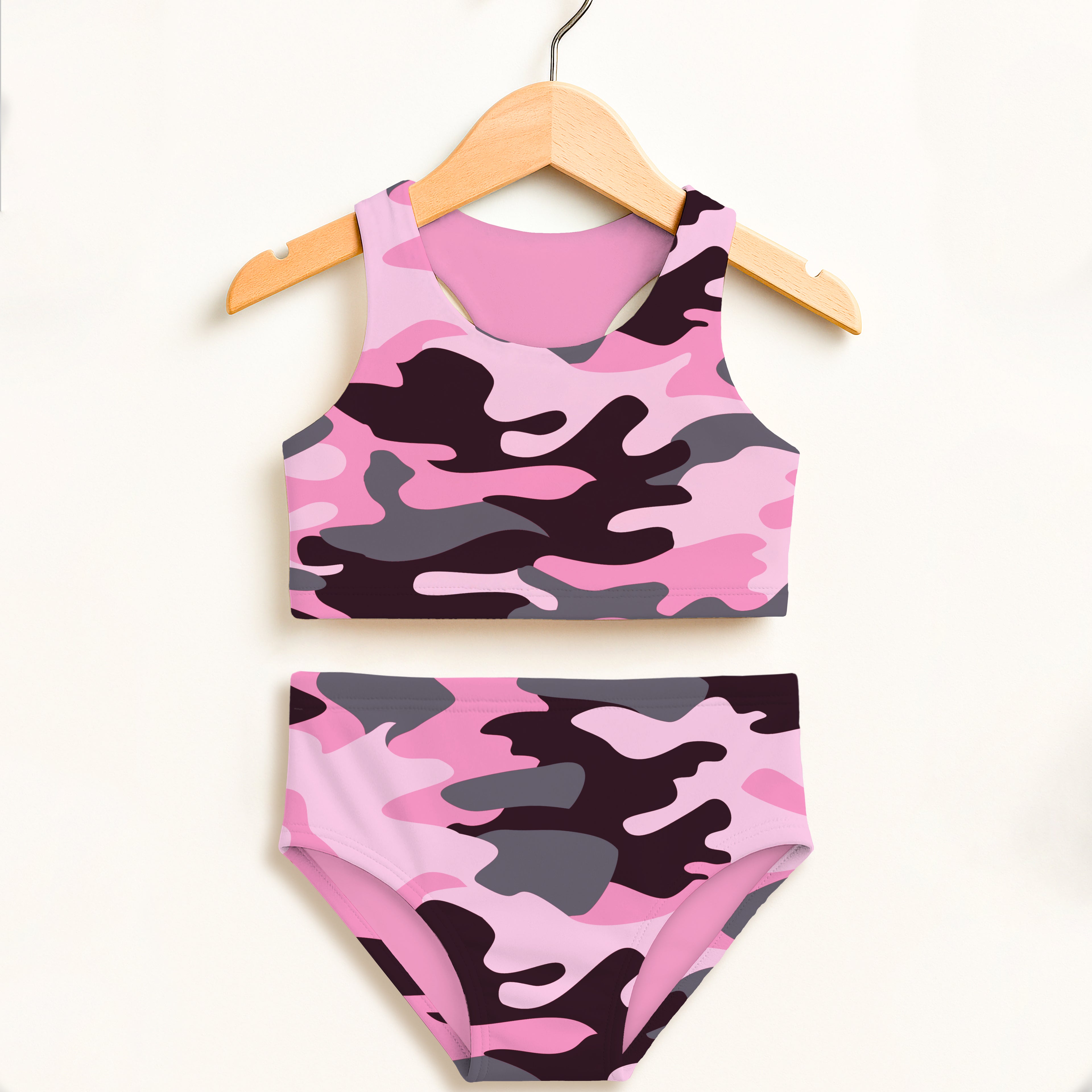 Girls pink and gray camouflage two piece swimsuit hanging on wooden hanger featuring double layered upf 50 high waisted comfort