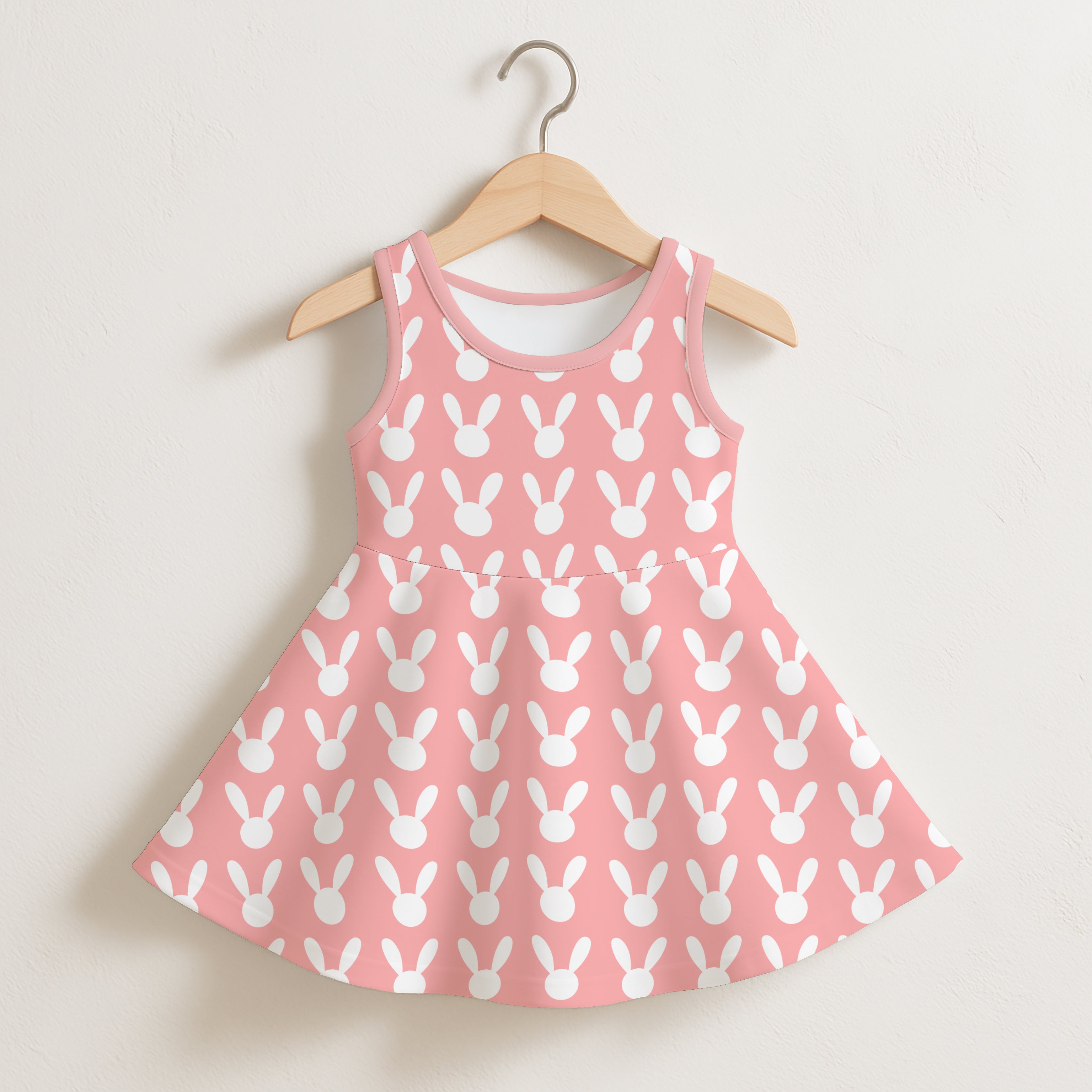 Girls pink sleeveless dress with white bunny silhouette pattern hanging on a wooden hanger