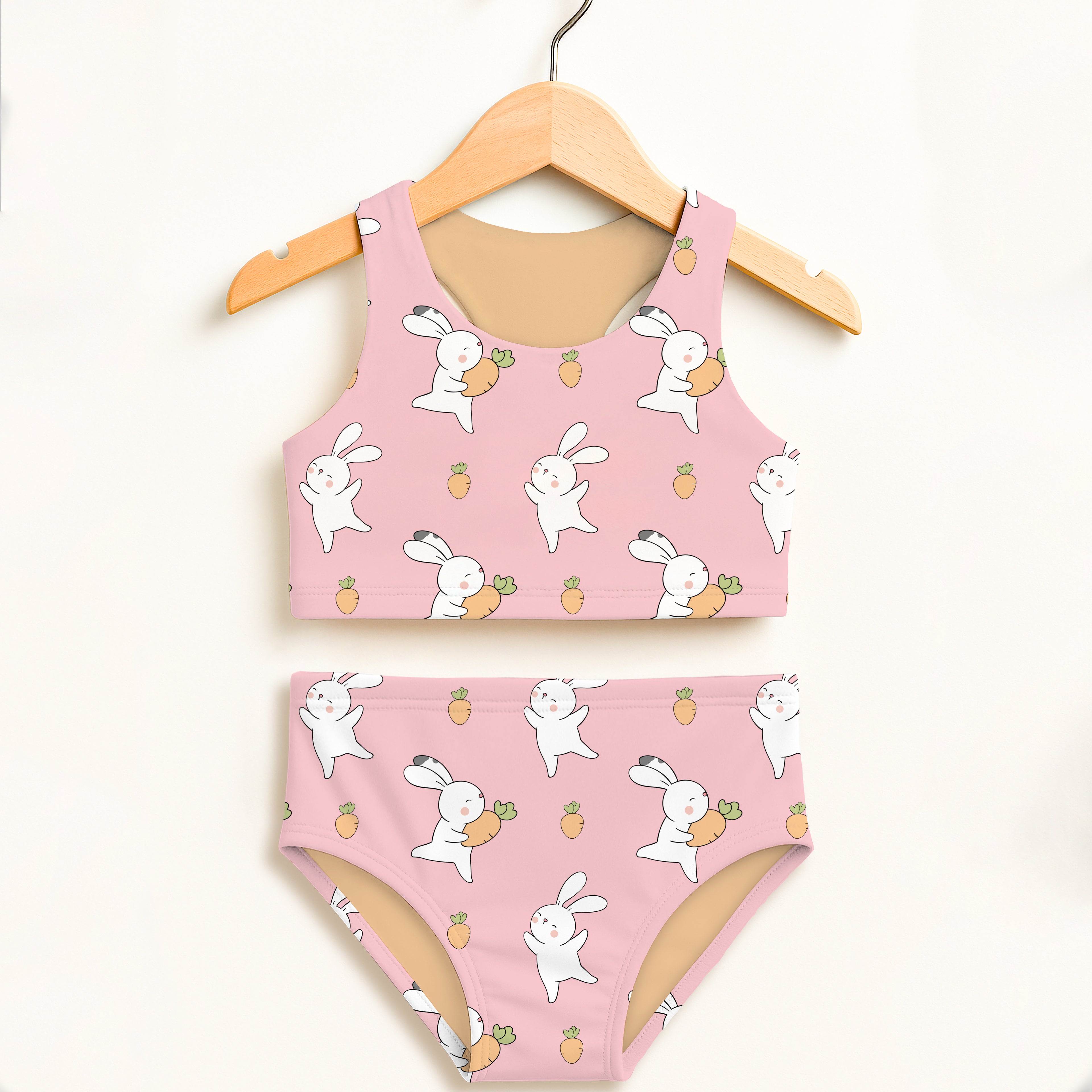 Girls pink bunny carrot two piece swimsuit with double layered fabric and upf 50 plus hanging on wooden hanger