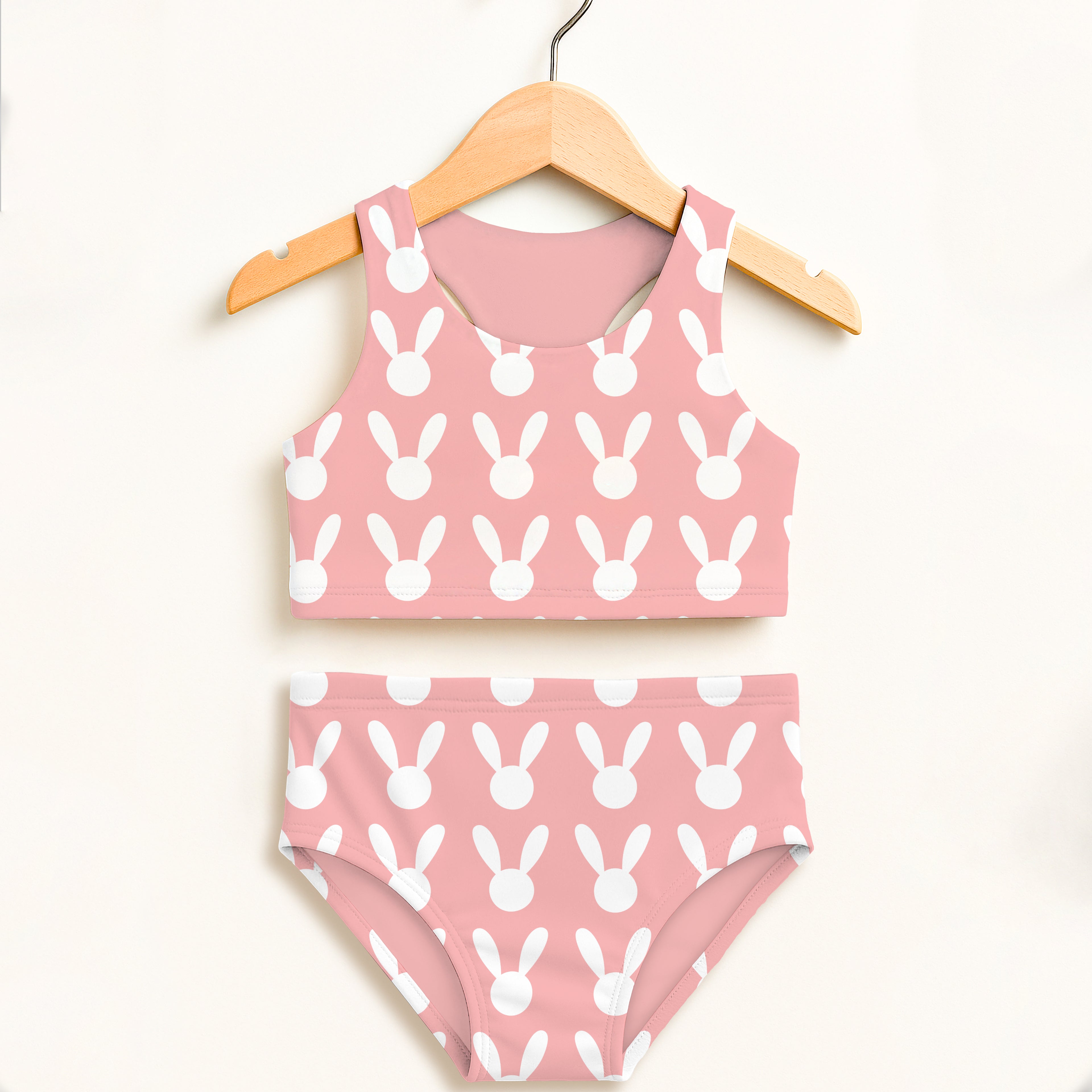 Girls pink bunny two piece swimsuit with double layered fabric and upf 50 plus hanging on a wooden hanger
