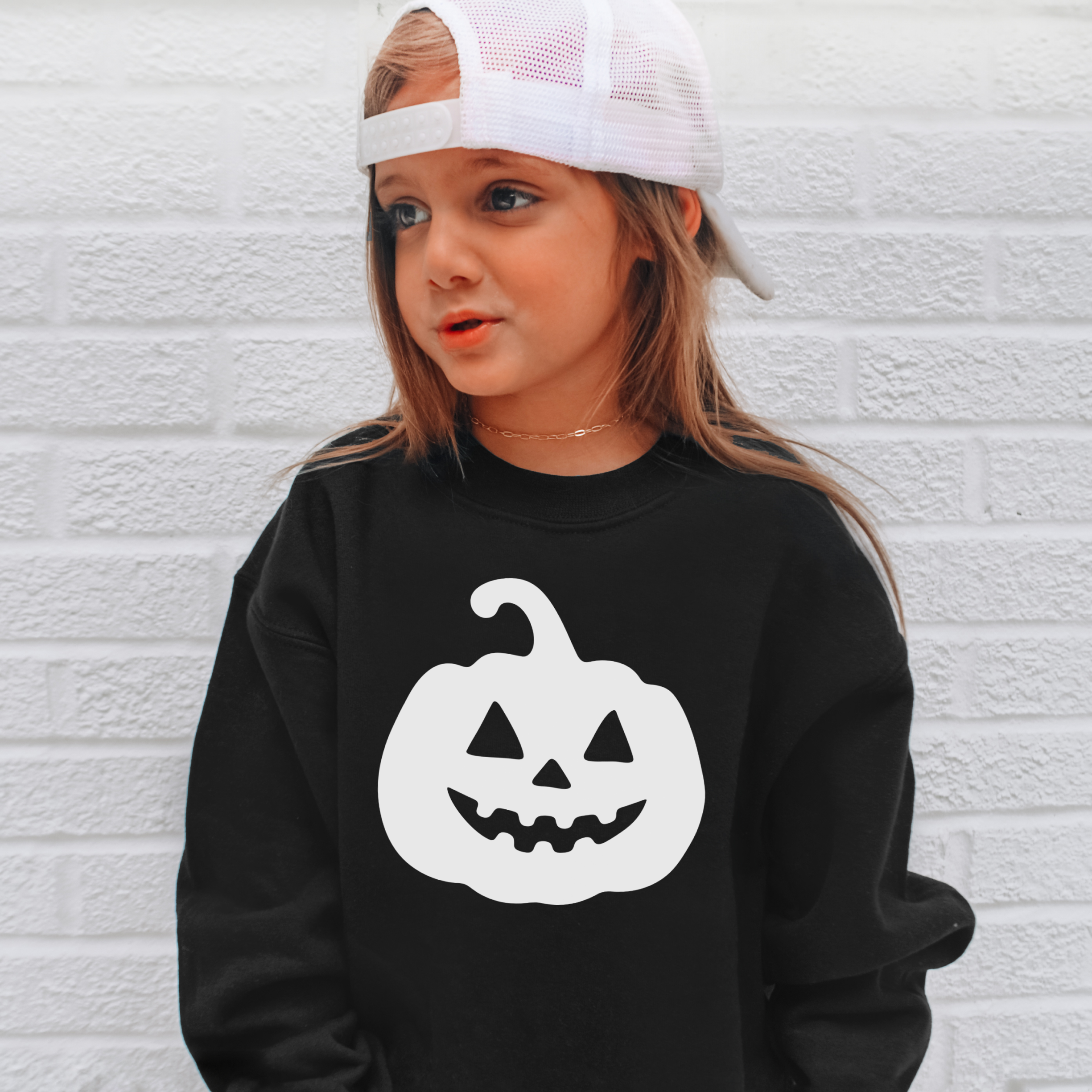 Black long-sleeved kids pumpkin sweatshirt with white jack-o-lantern face graphic for Halloween pullover