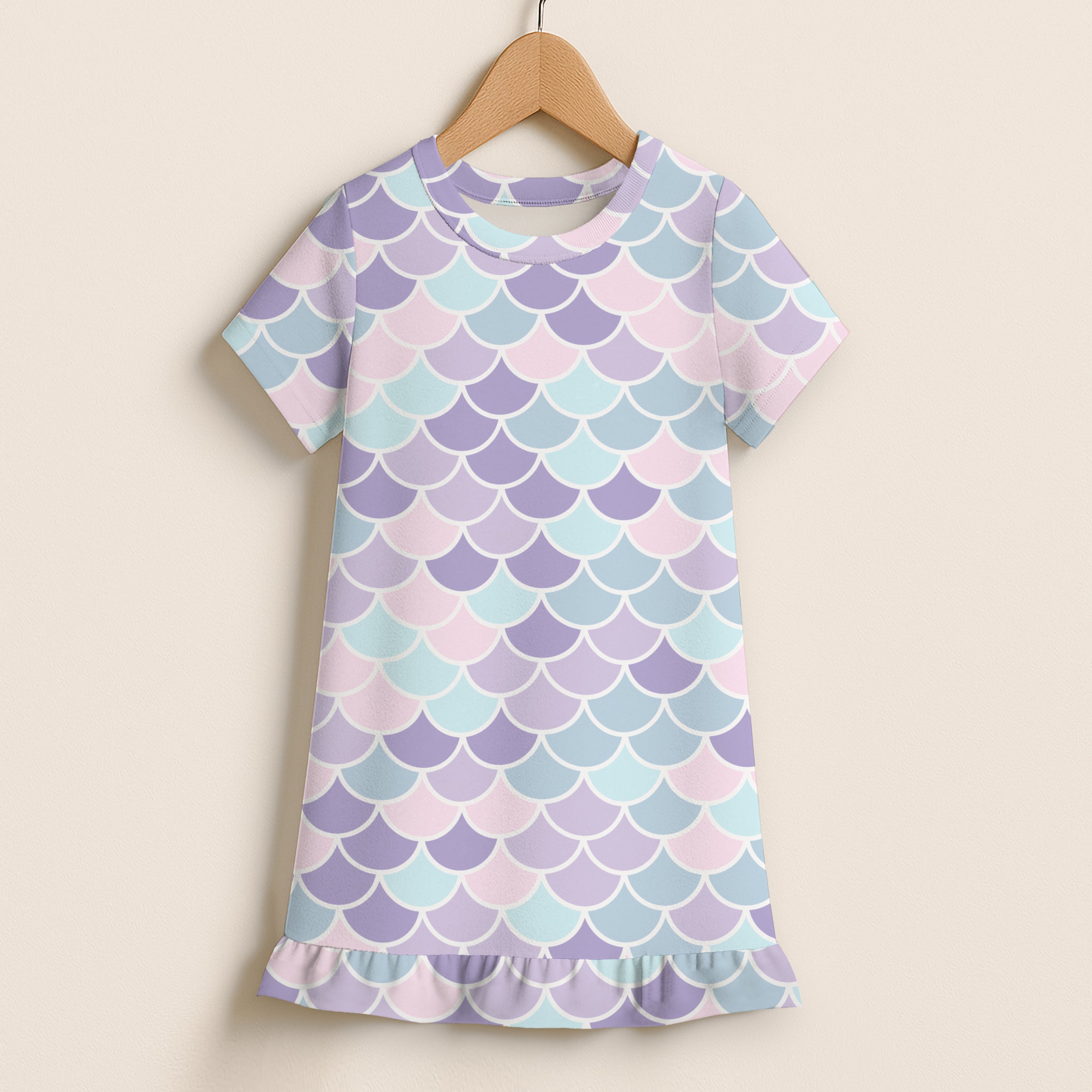 Girls pastel mermaid scales short sleeve dress with soft pastel colors and ruffled hem hanging on wooden hanger