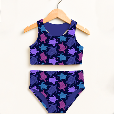 Two-piece swimsuit with turtle pattern on a hanger against a white background