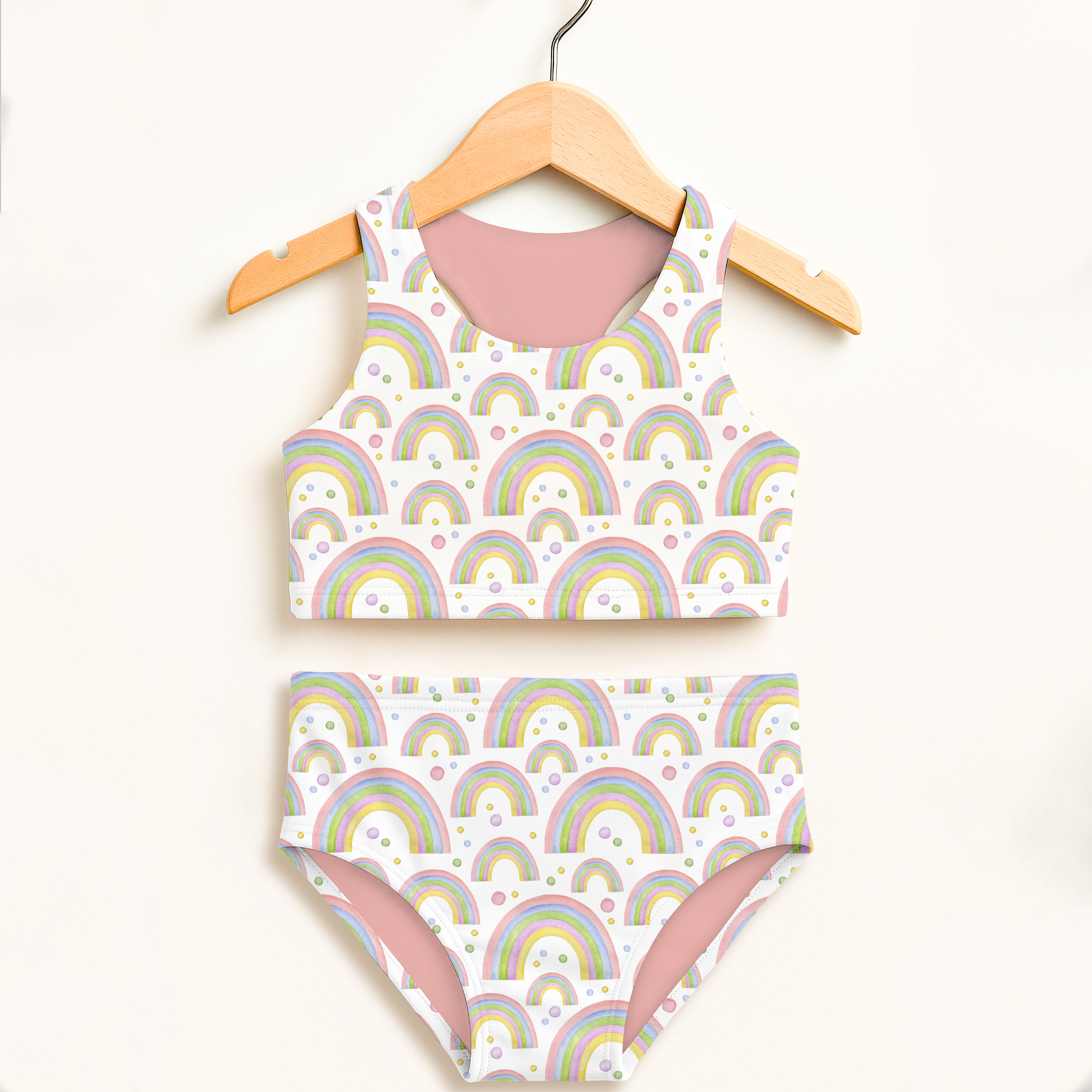 Children's swimsuit with rainbow pattern on a hanger against a white background