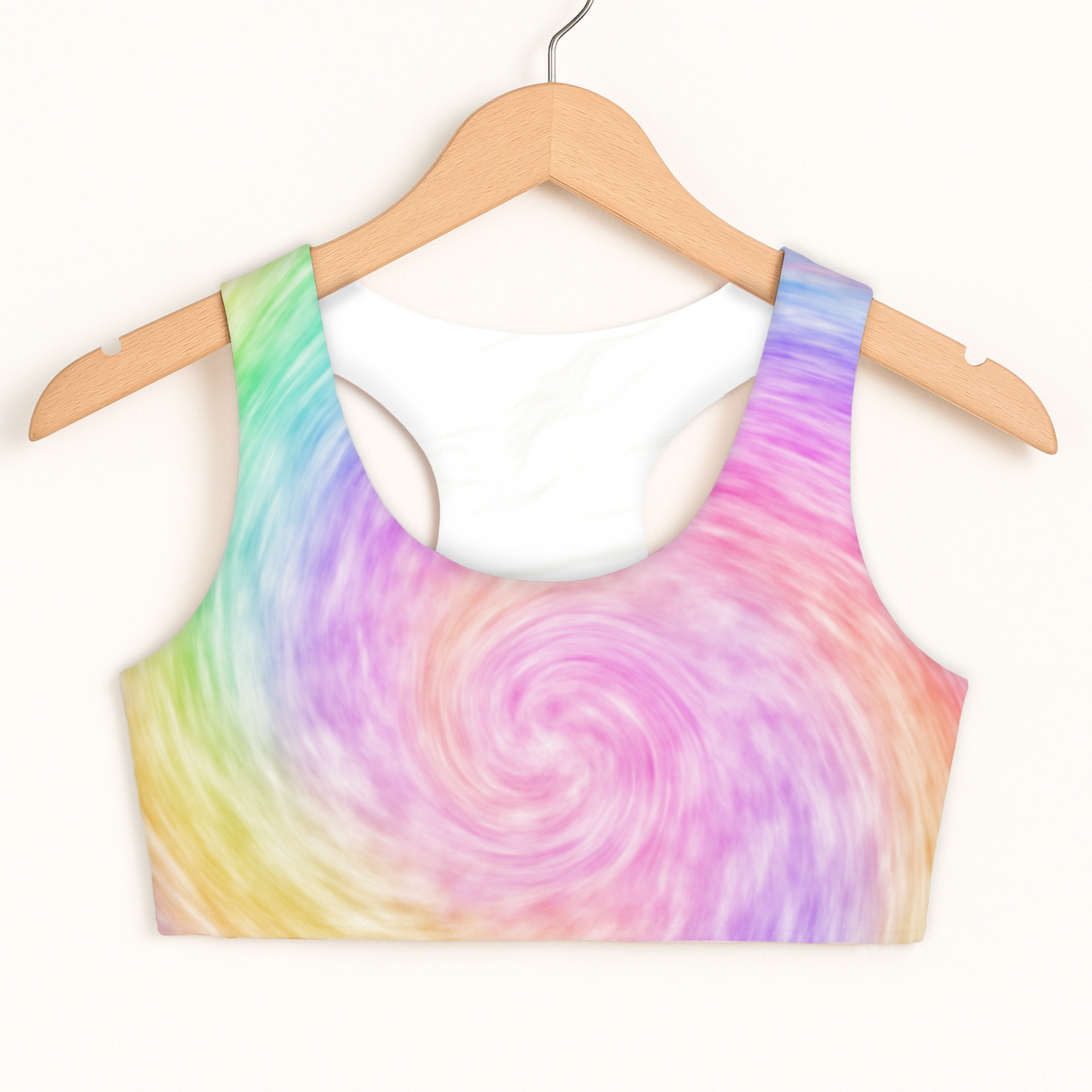 Girls rainbow tie dye sports bra with vibrant swirl pattern and white inner lining on wooden hanger for quick drying and comfort