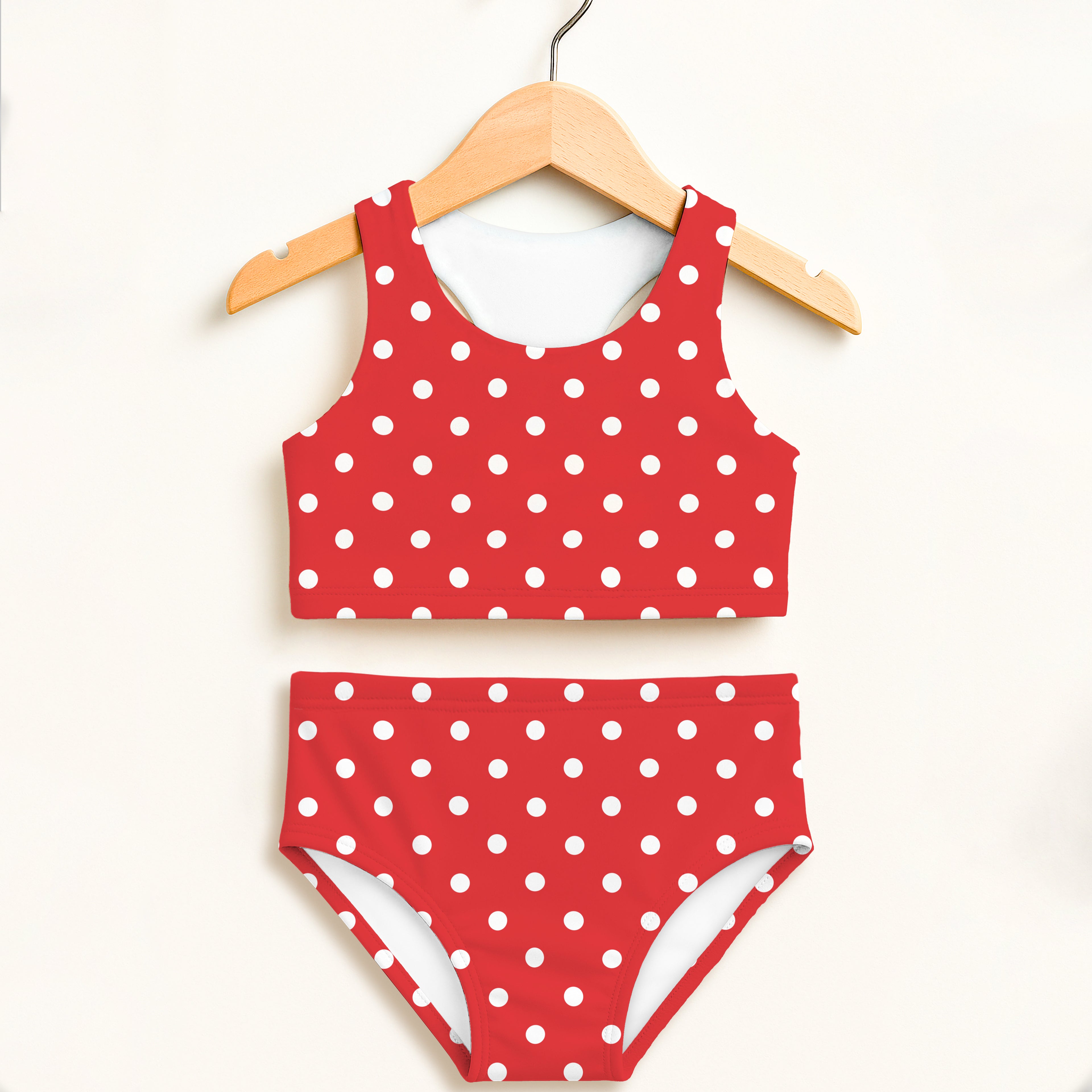 Girls red and white polka dot two-piece swimsuit with double layered high waisted comfort and upf 50+ protection hanging on wooden hanger