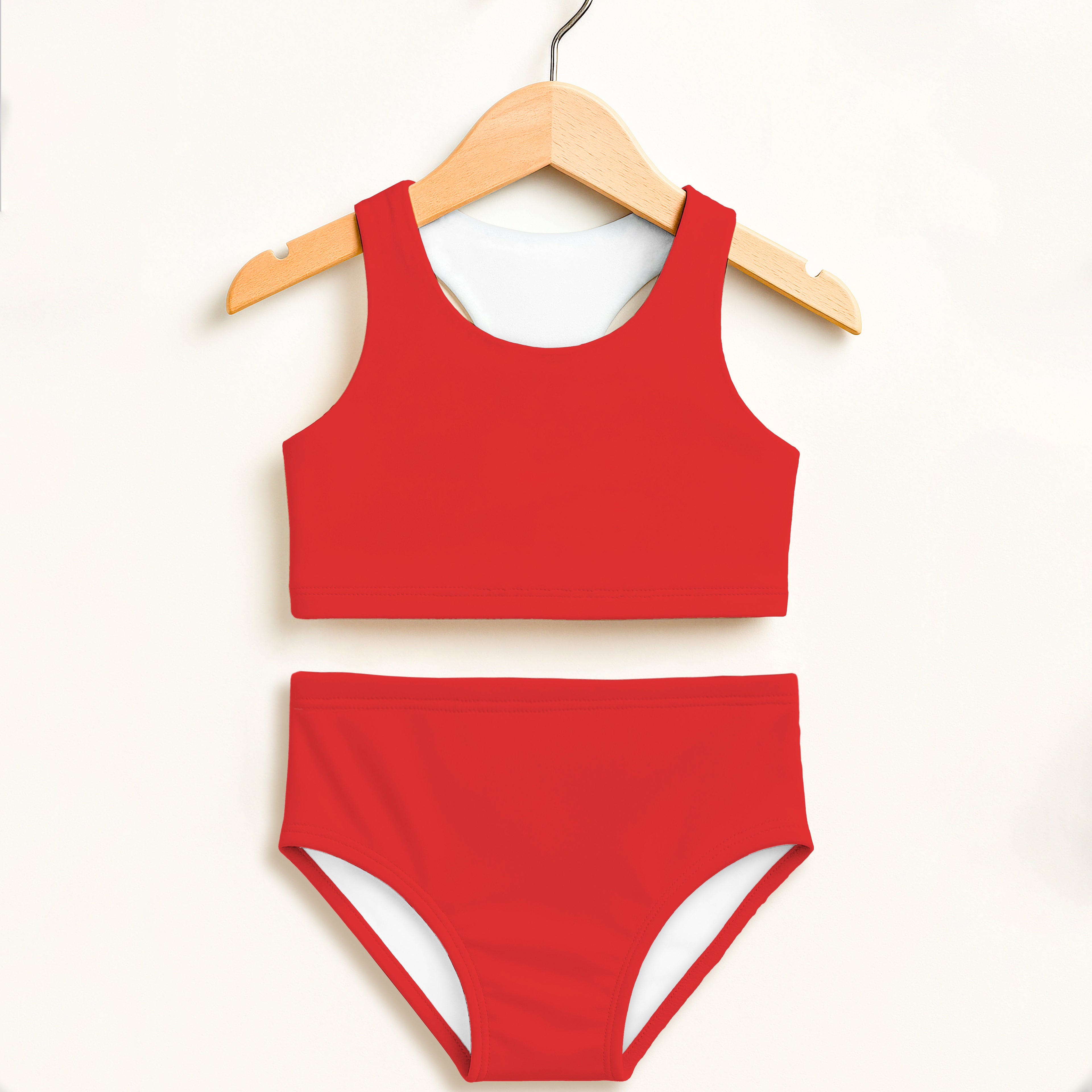 Girls red two piece swimsuit with white side lining hanging on wooden hanger featuring double layered UPF 50+ fabric