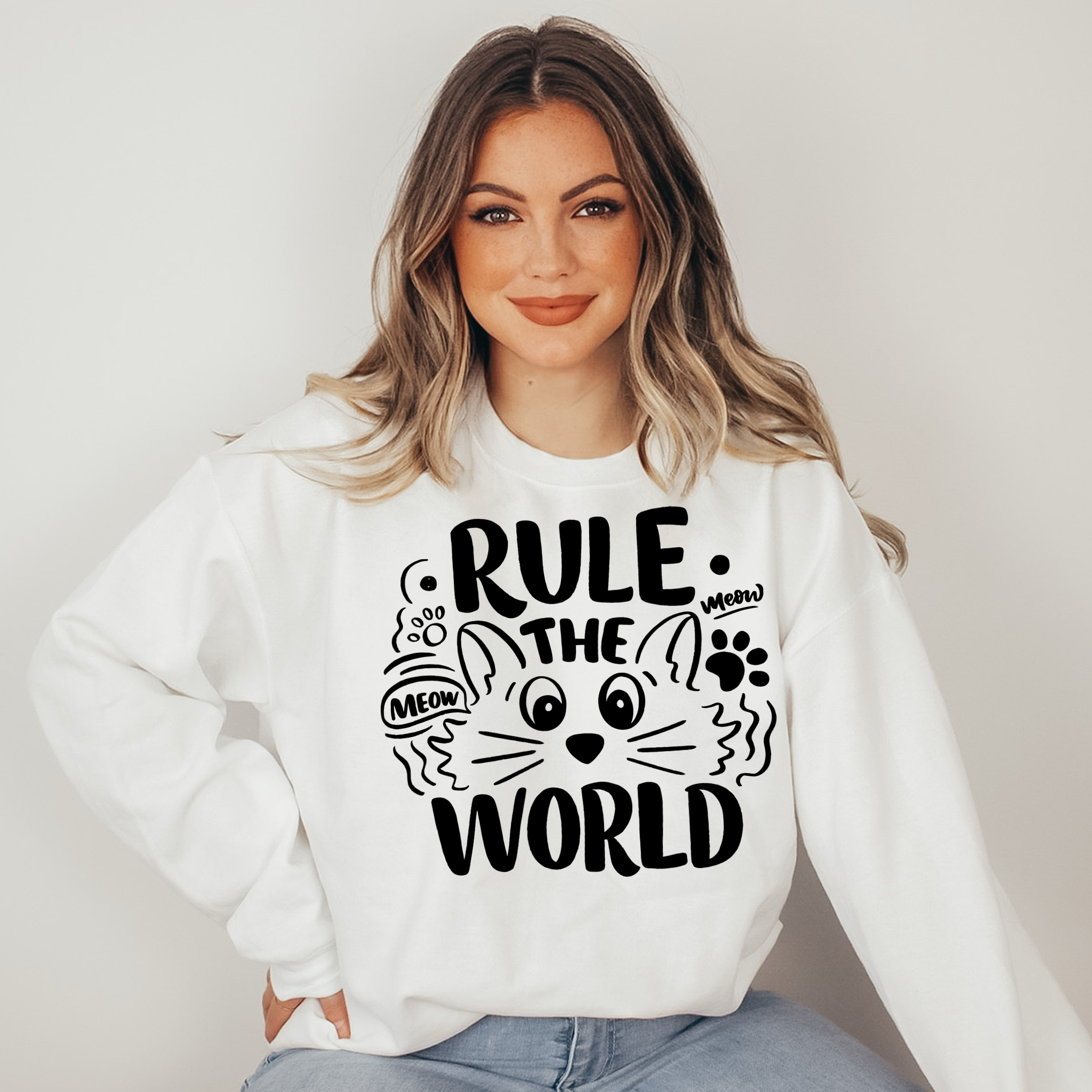 Woman wearing a white sweatshirt with a cat-themed design and text.