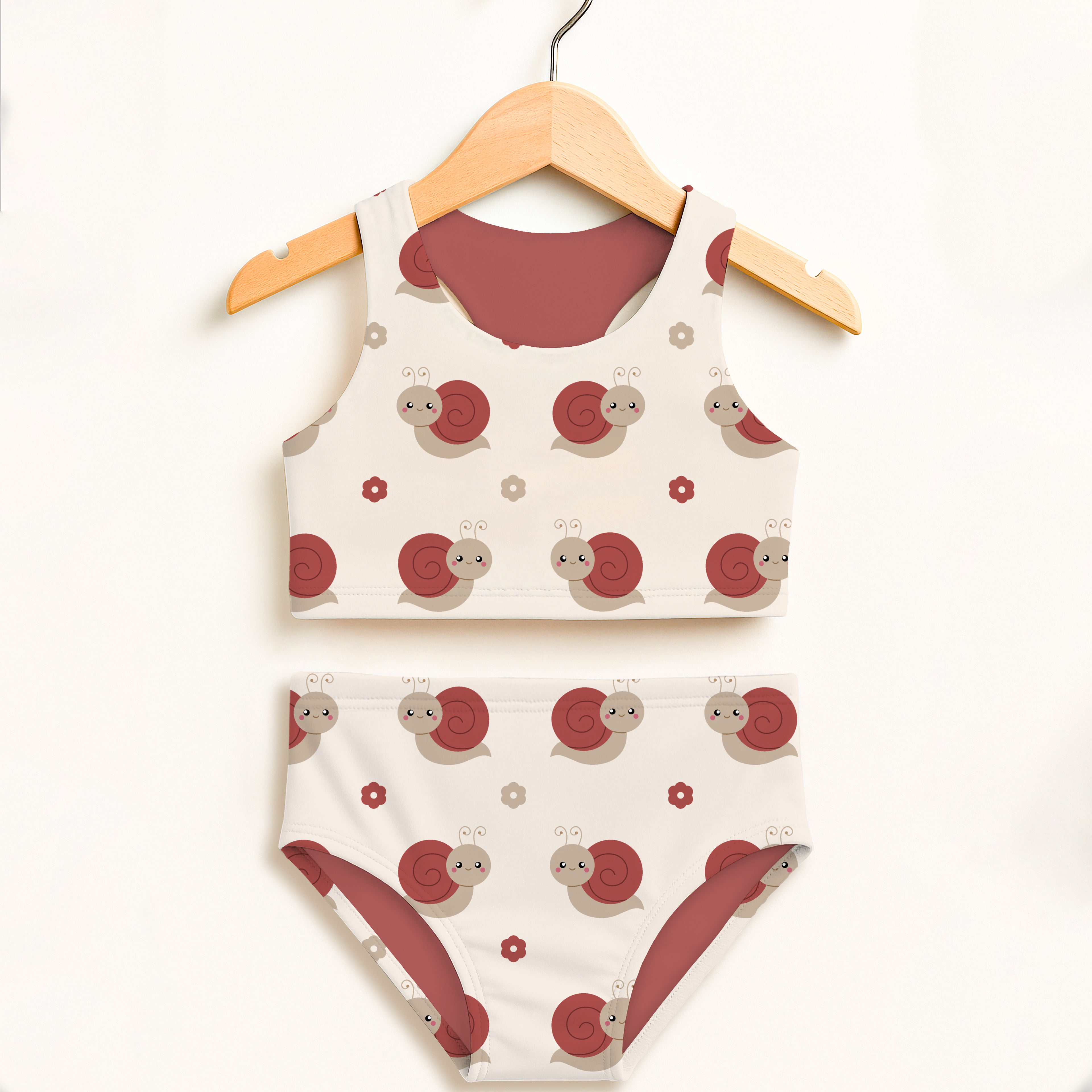 A charming white girls red snail two piece swimsuit with playful red and gray cartoon snails on a wooden hanger