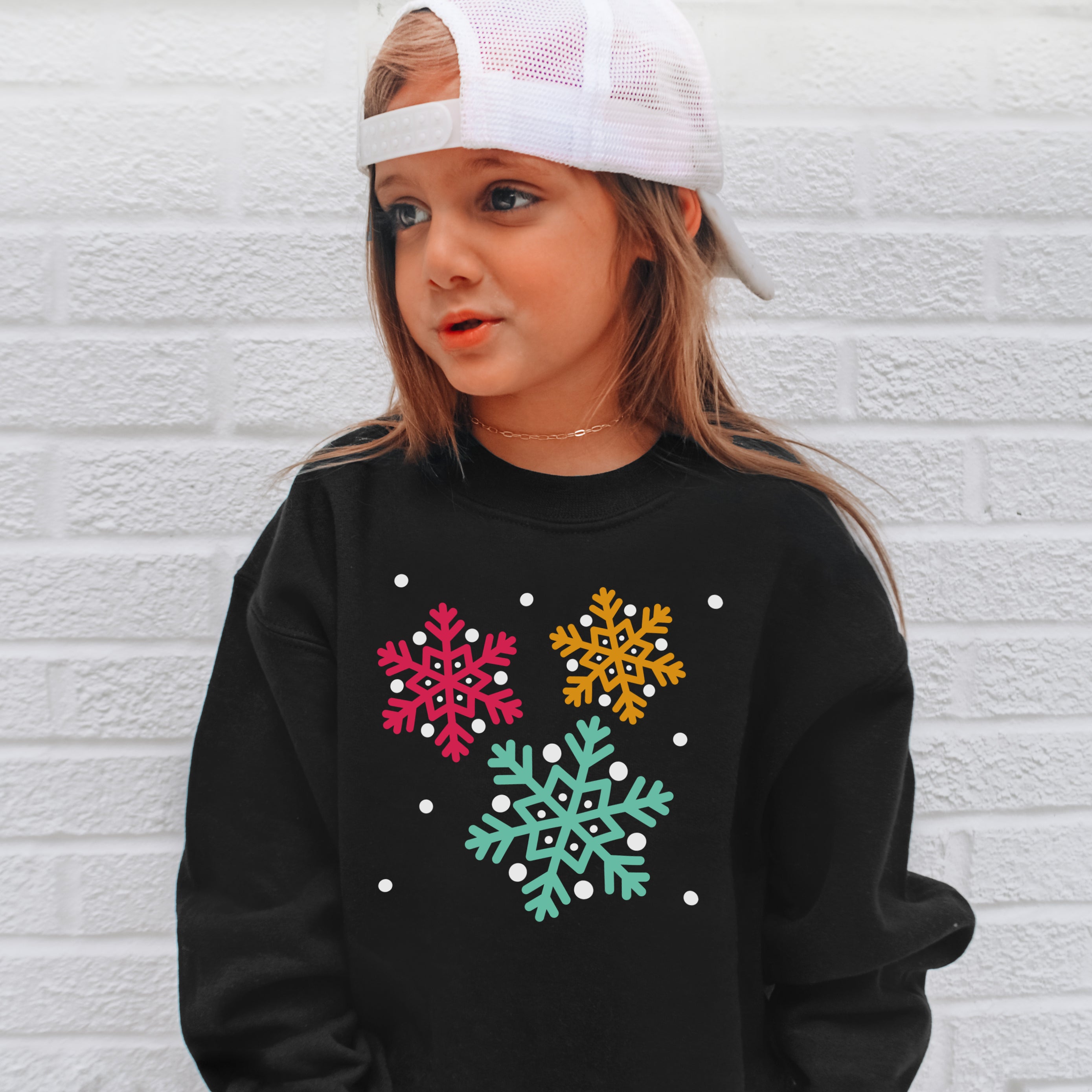 Black long-sleeved kids sweatshirt with colorful pink yellow and teal snowflake designs for fun winter wear
