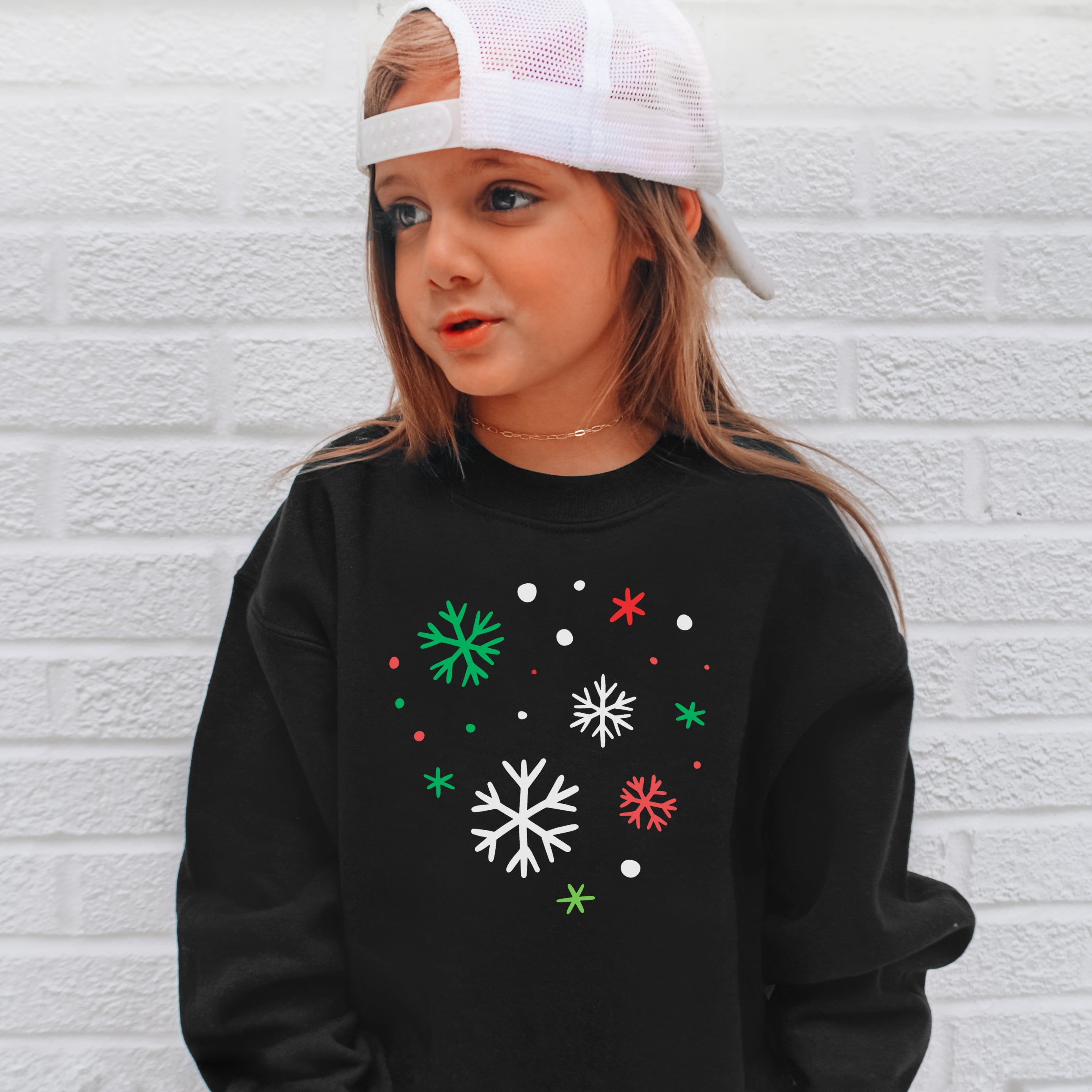 Kids black long-sleeved sweatshirt with festive white green and red snowflake pattern perfect for winter Christmas wear
