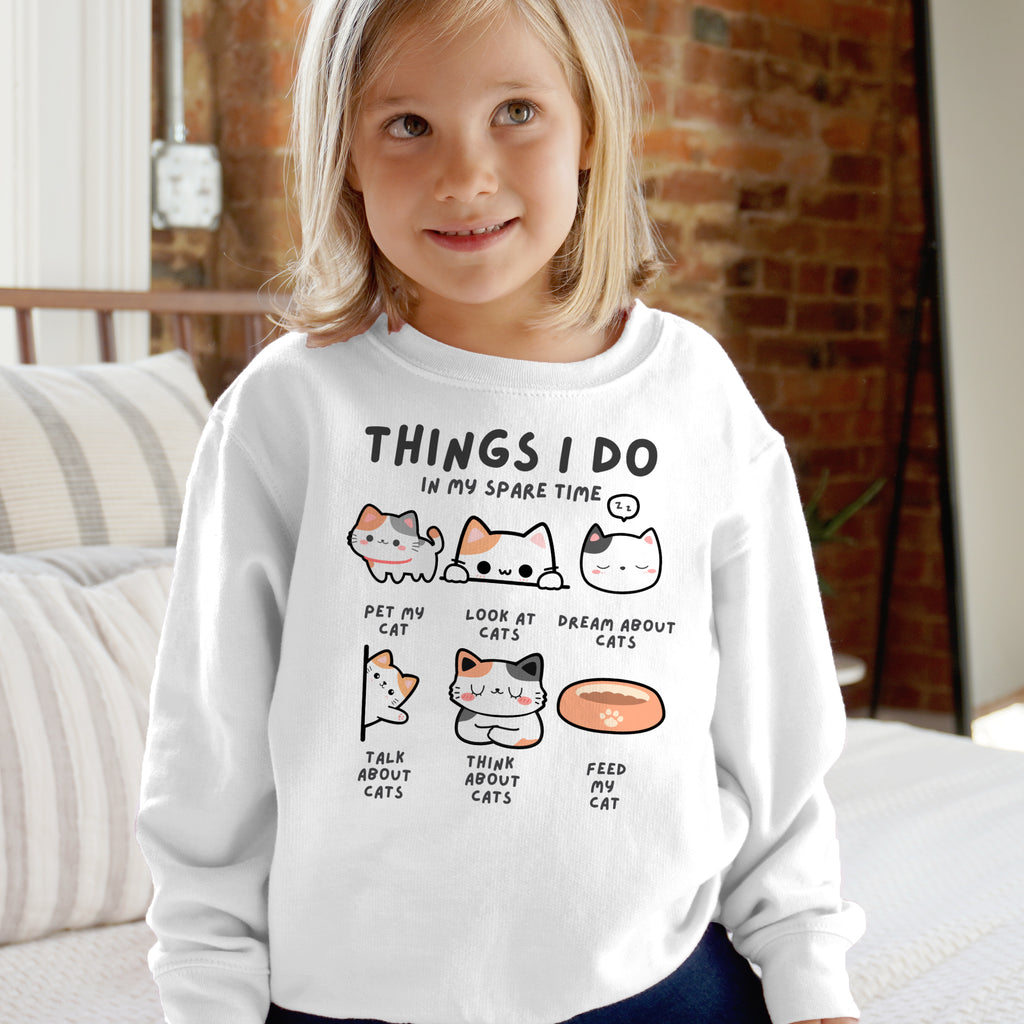 Child wearing a white sweatshirt with cat-themed text and illustrations.