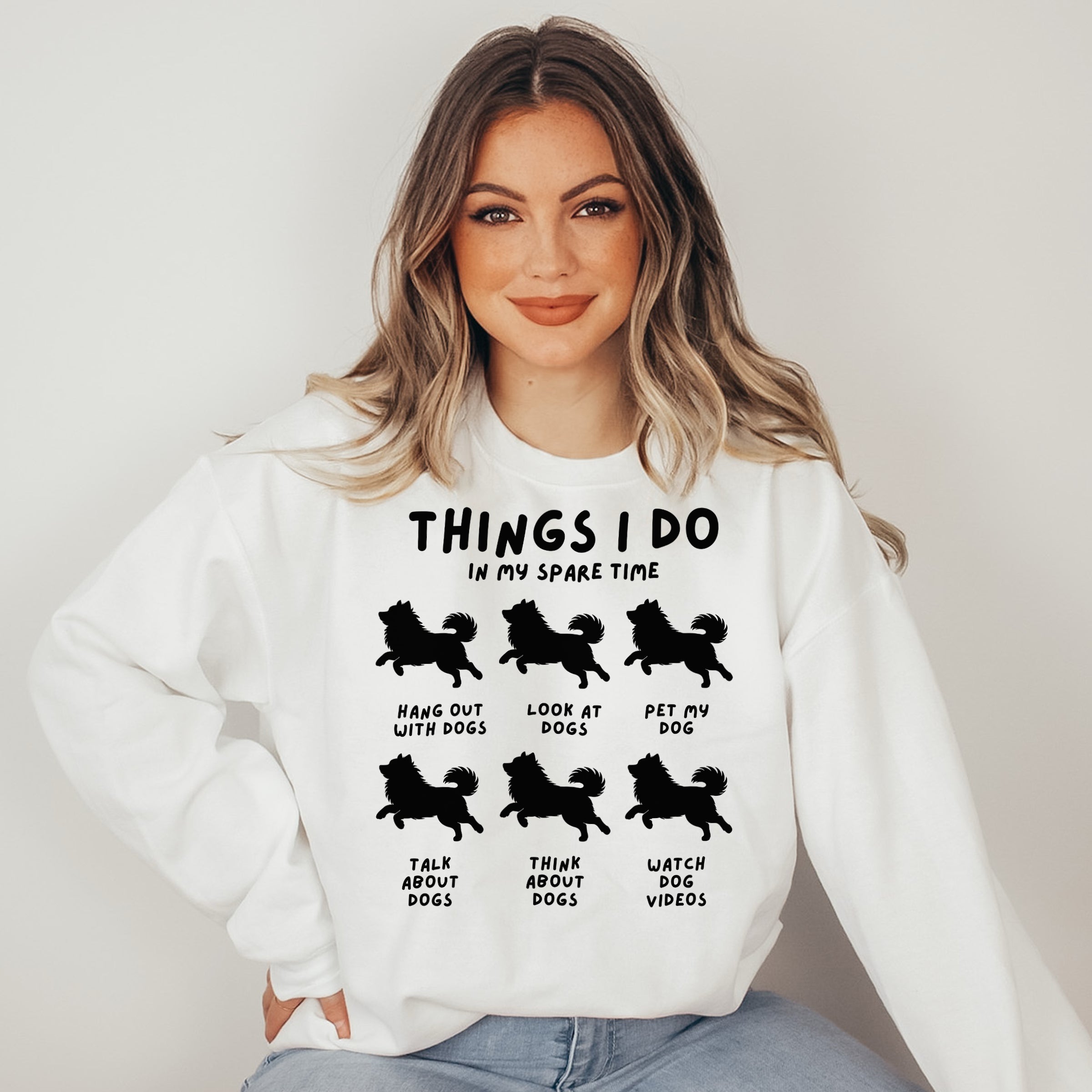 Woman wearing a white sweatshirt with black text and dog illustrations on a plain background