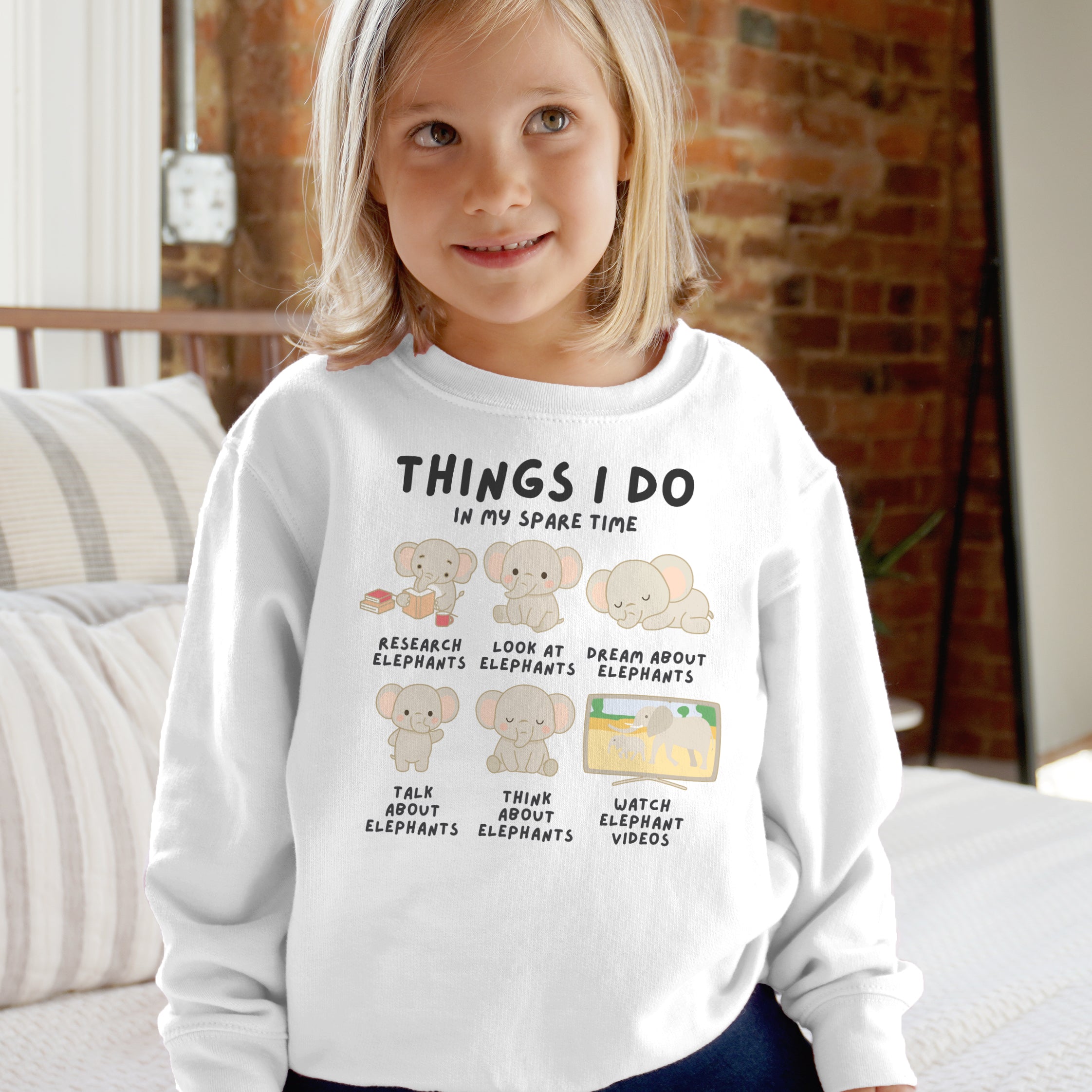 Child wearing a white sweatshirt with elephant-themed text and graphics.