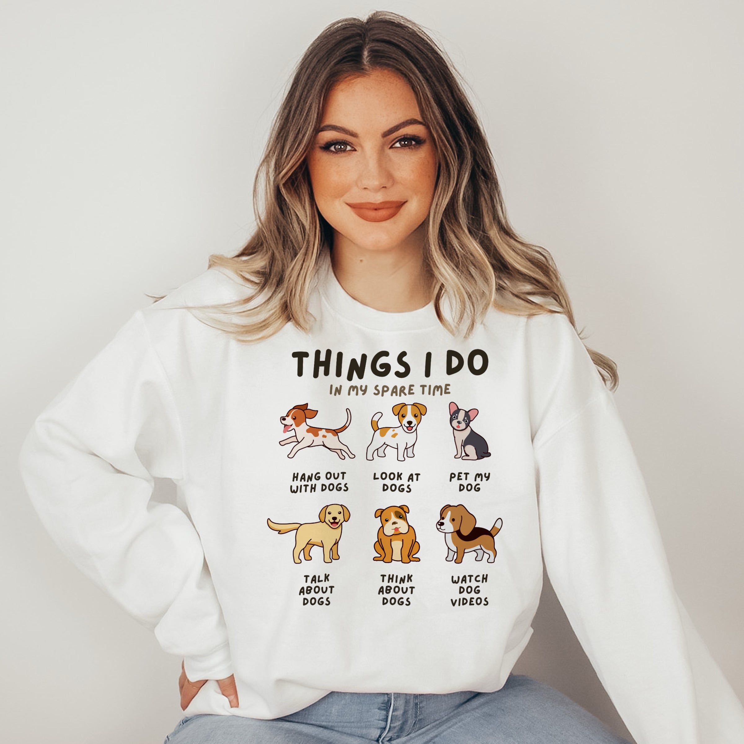 Woman wearing a white sweatshirt with dog-themed graphics and text.