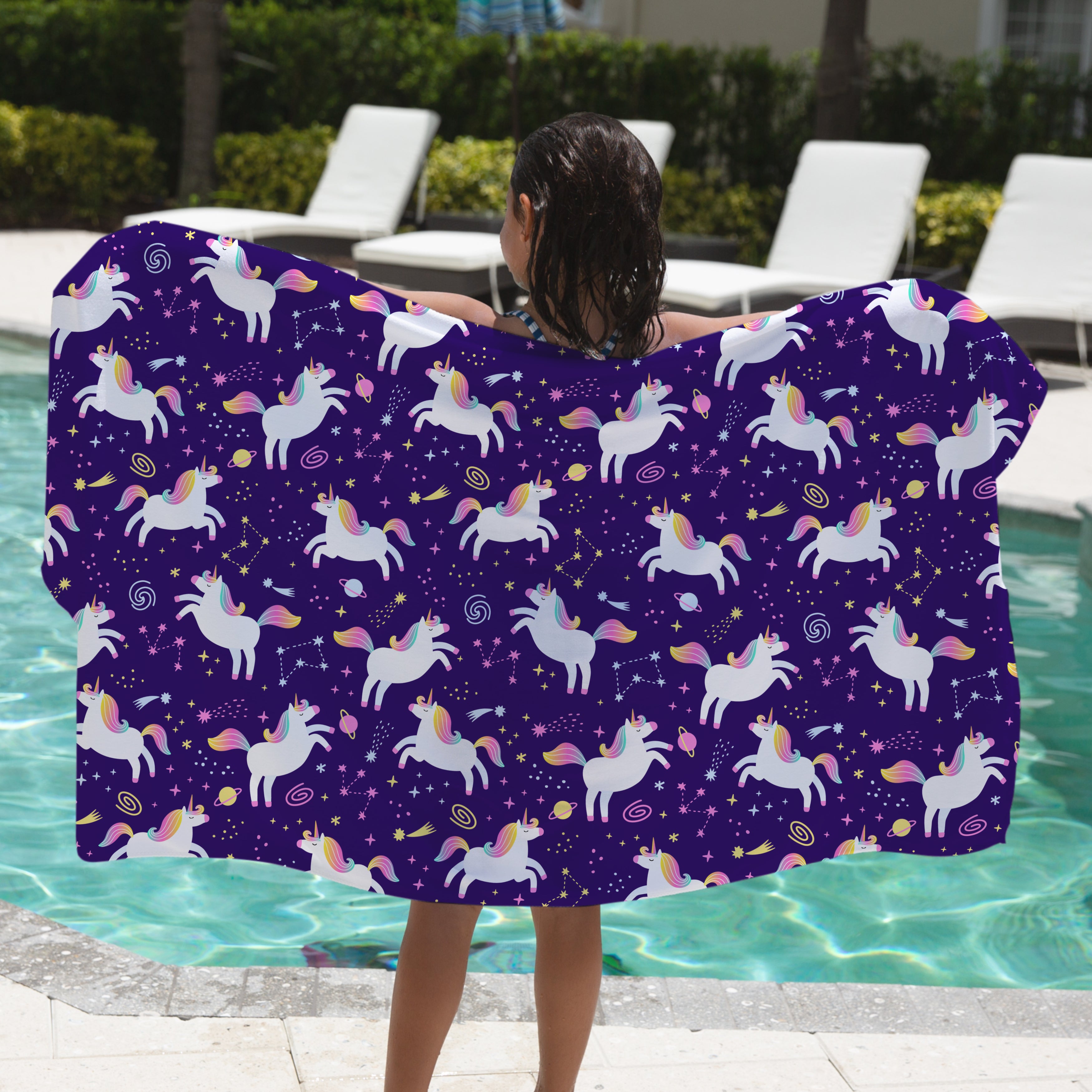 Person holding a purple unicorn patterned towel by a pool