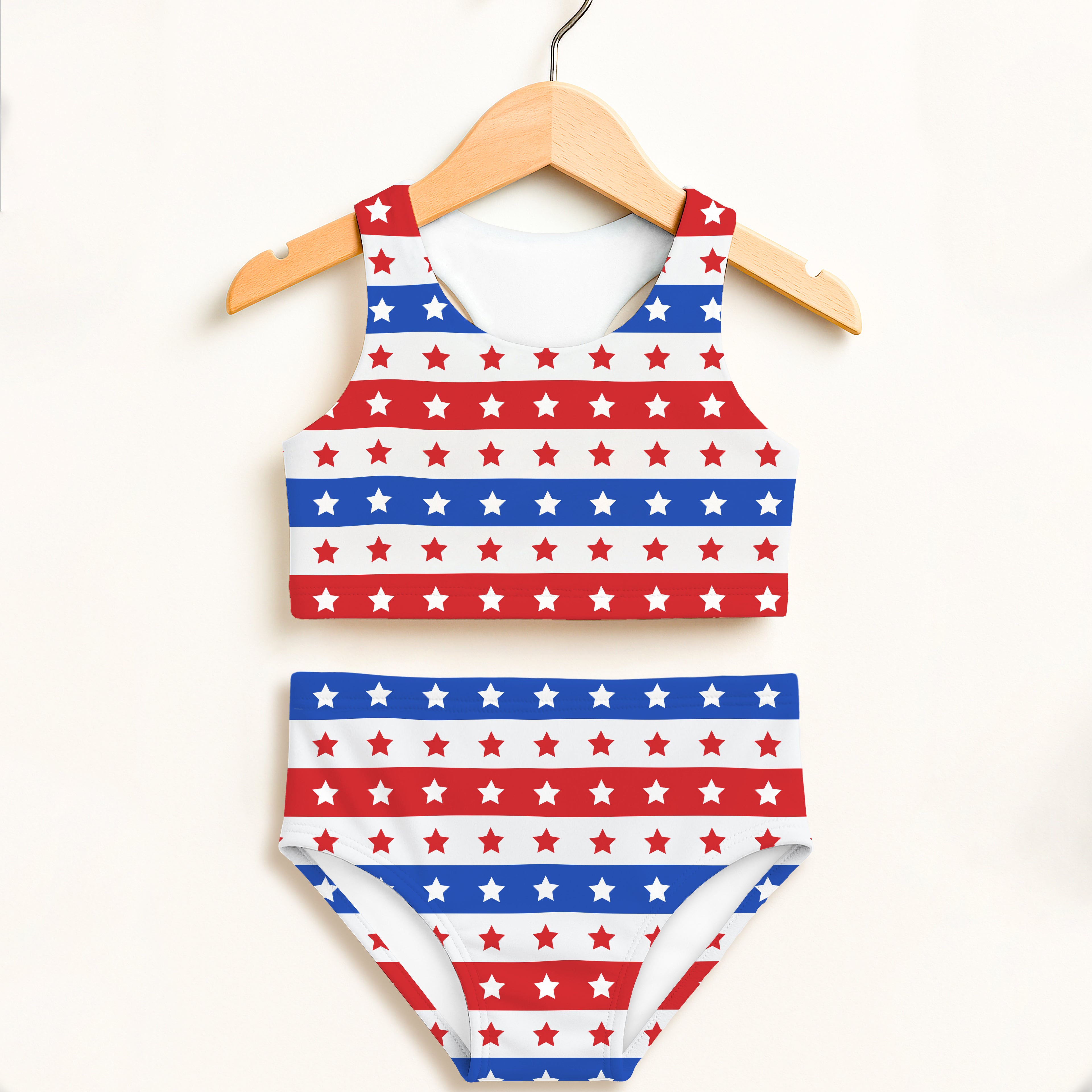 Girls red white and blue star patterned two piece swimsuit on wooden hanger with double layered upf 50 plus fabric