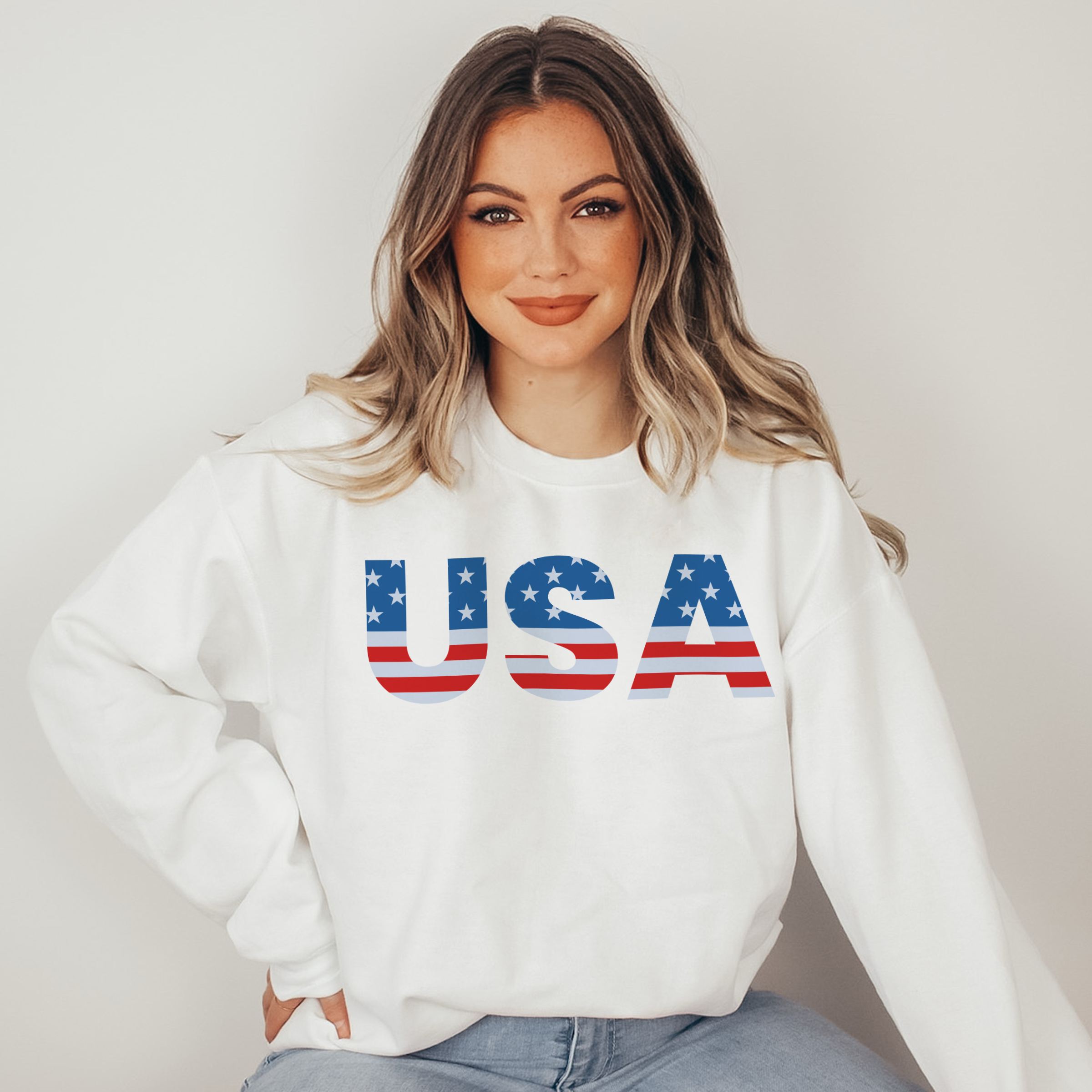 Woman wearing a white sweatshirt with 'USA' printed on it against a plain background
