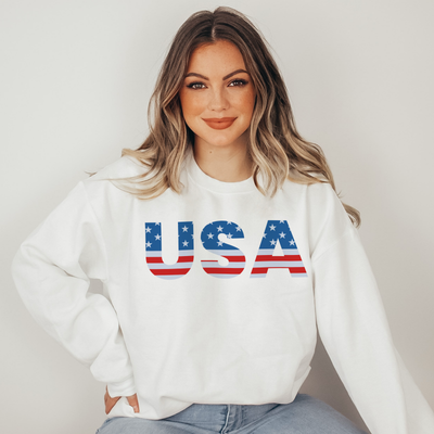 Woman wearing a white sweatshirt with 'USA' printed on it against a plain background