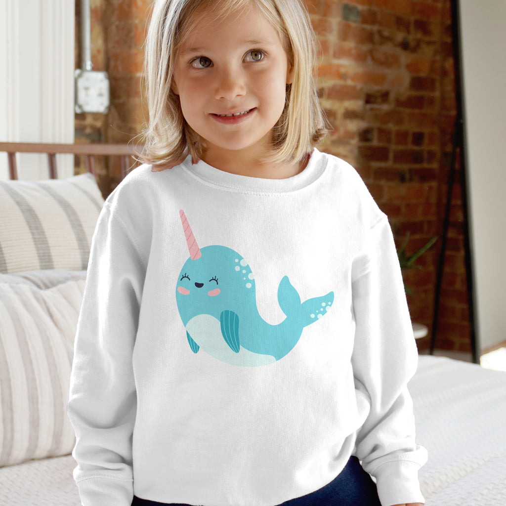 White long-sleeved kids sweatshirt with a cute light blue narwhal with pink horn printed on the front
