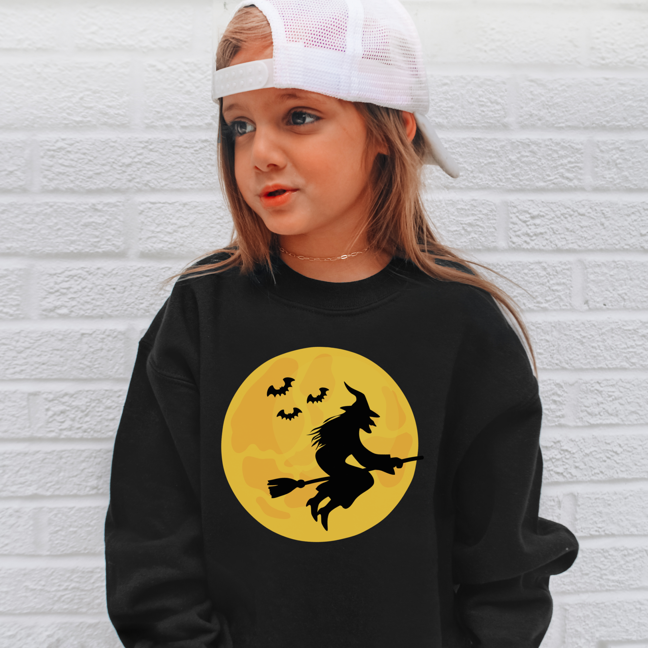 Kids witch halloween sweatshirt in black with bold yellow moon and silhouette of witch flying with bats on front