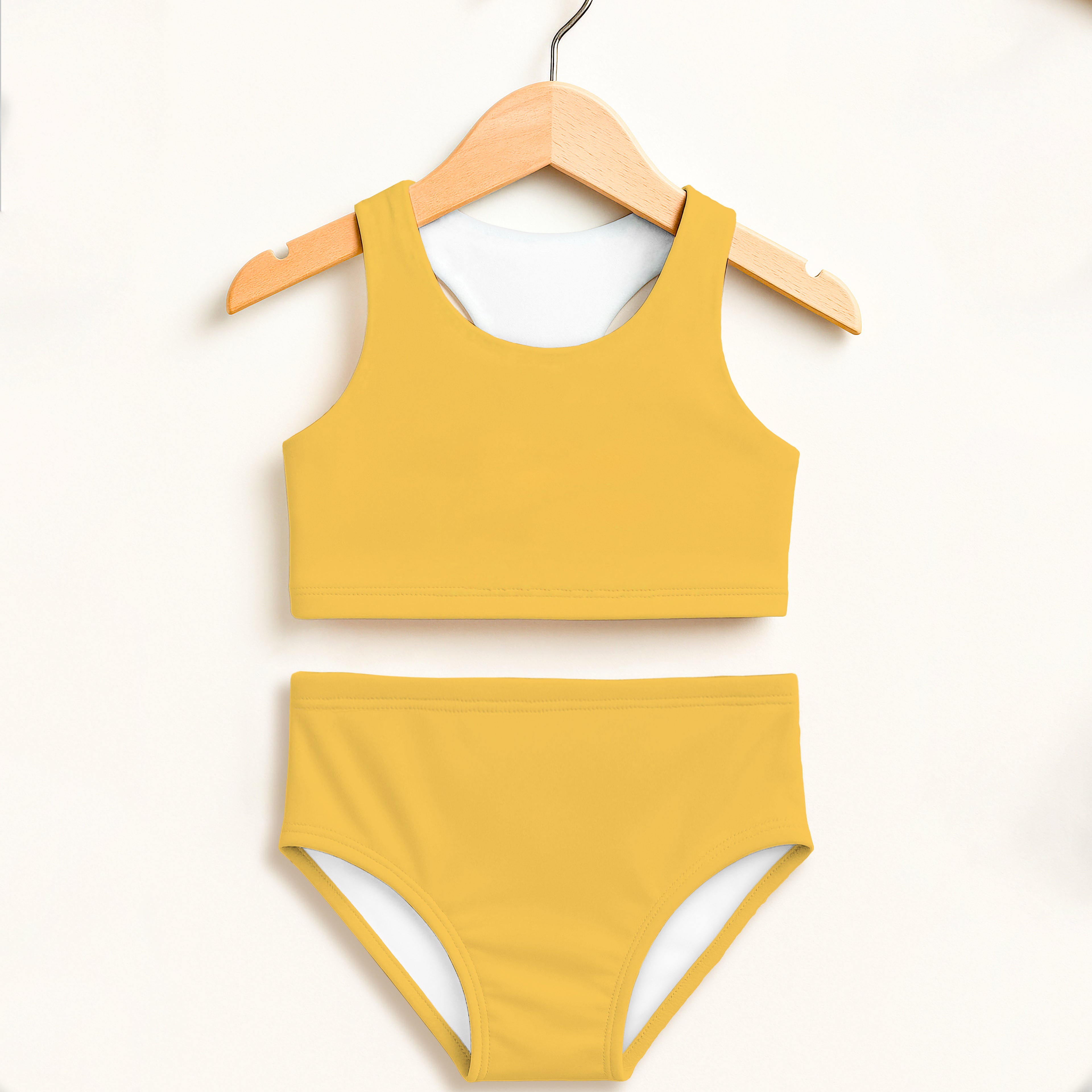 Girls yellow two-piece swimsuit with white lining hanging on wooden hanger double layered UPF 50+ high waisted comfort